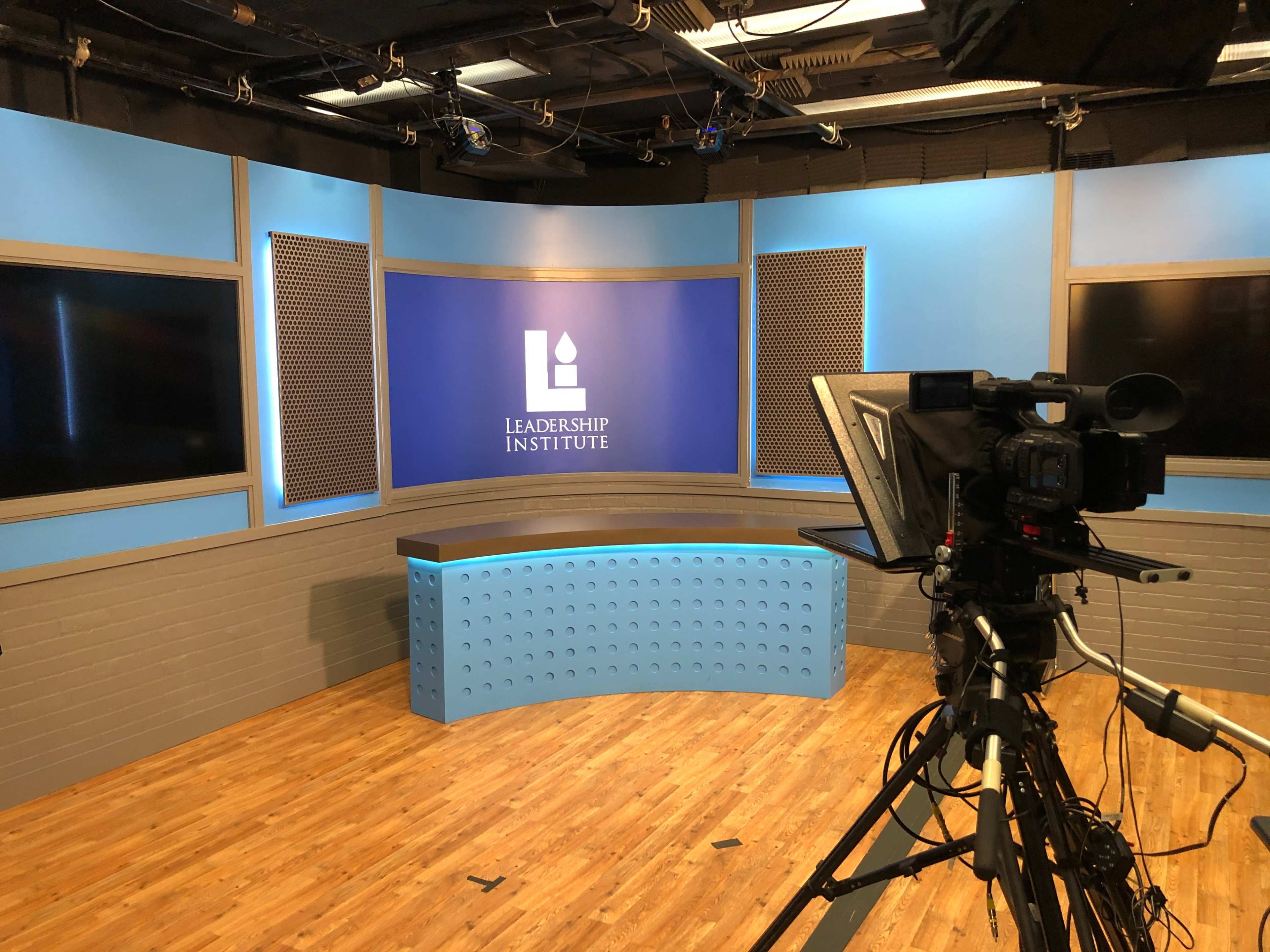 A television studio is set up with a blue backdrop featuring the text "Leadership Institute" and a camera positioned to capture the scene.