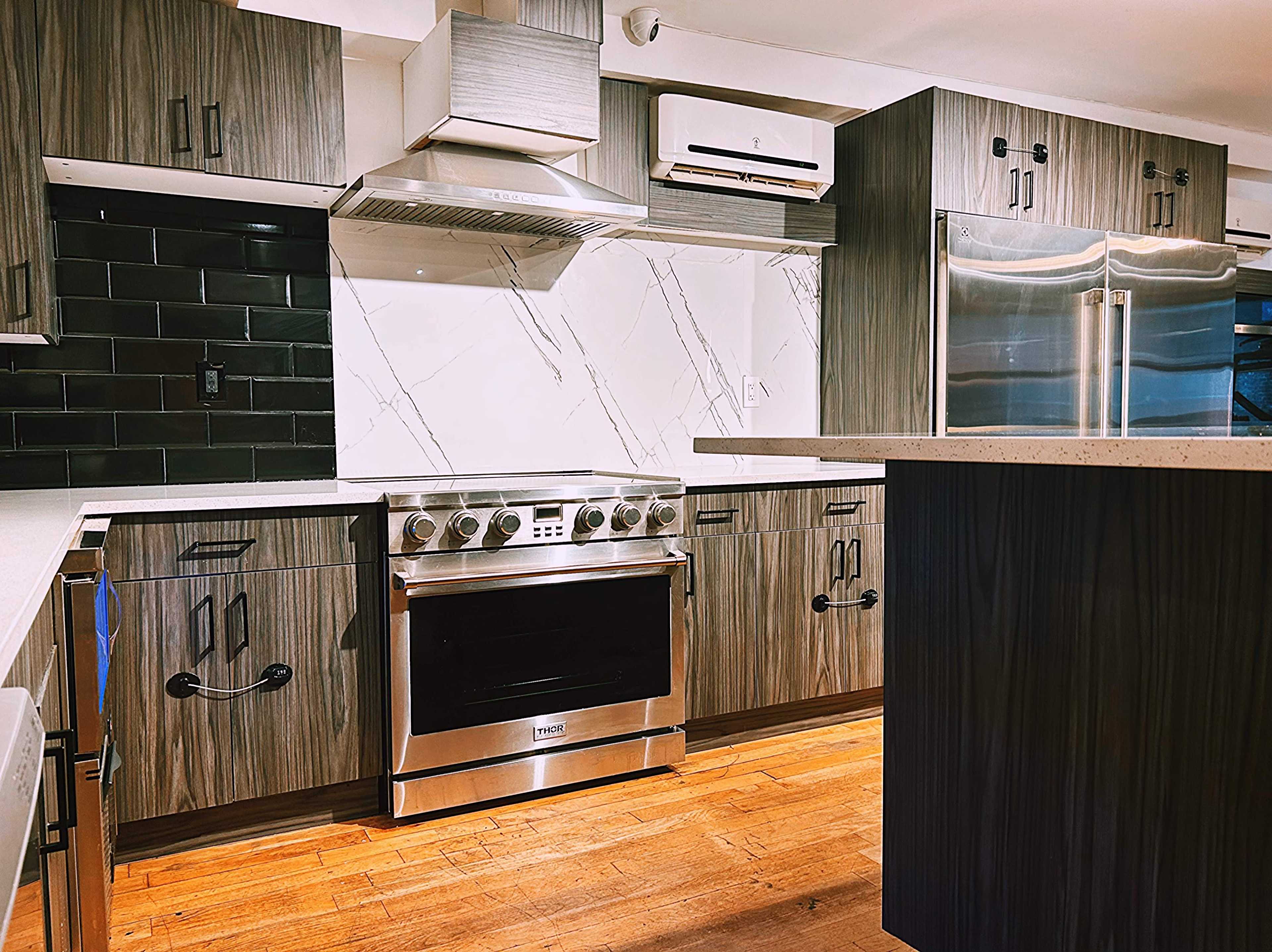 The image shows a modern kitchen featuring dark wooden cabinets, a stainless steel stove, and a marble-patterned backsplash.