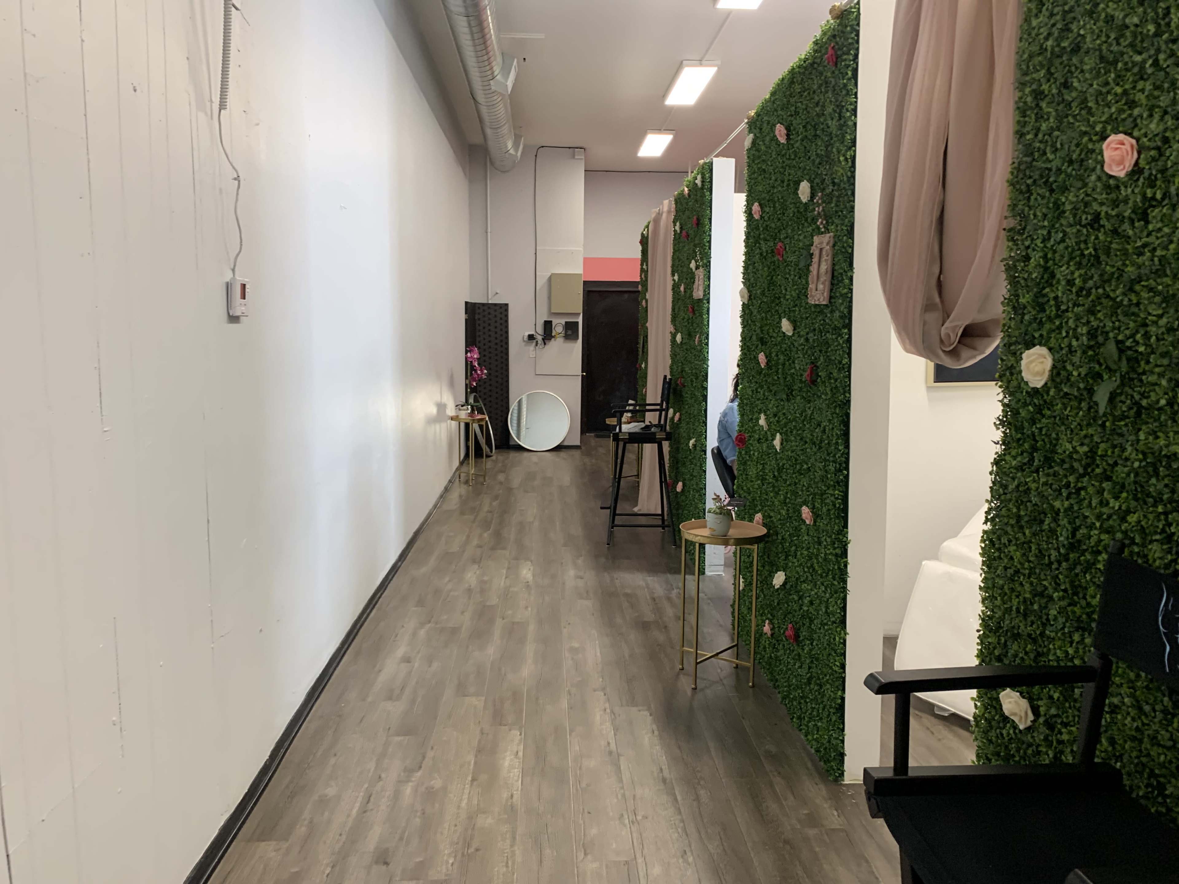 A long hallway features greenery-covered walls with decorative flowers, leading to various rooms and mirrors.