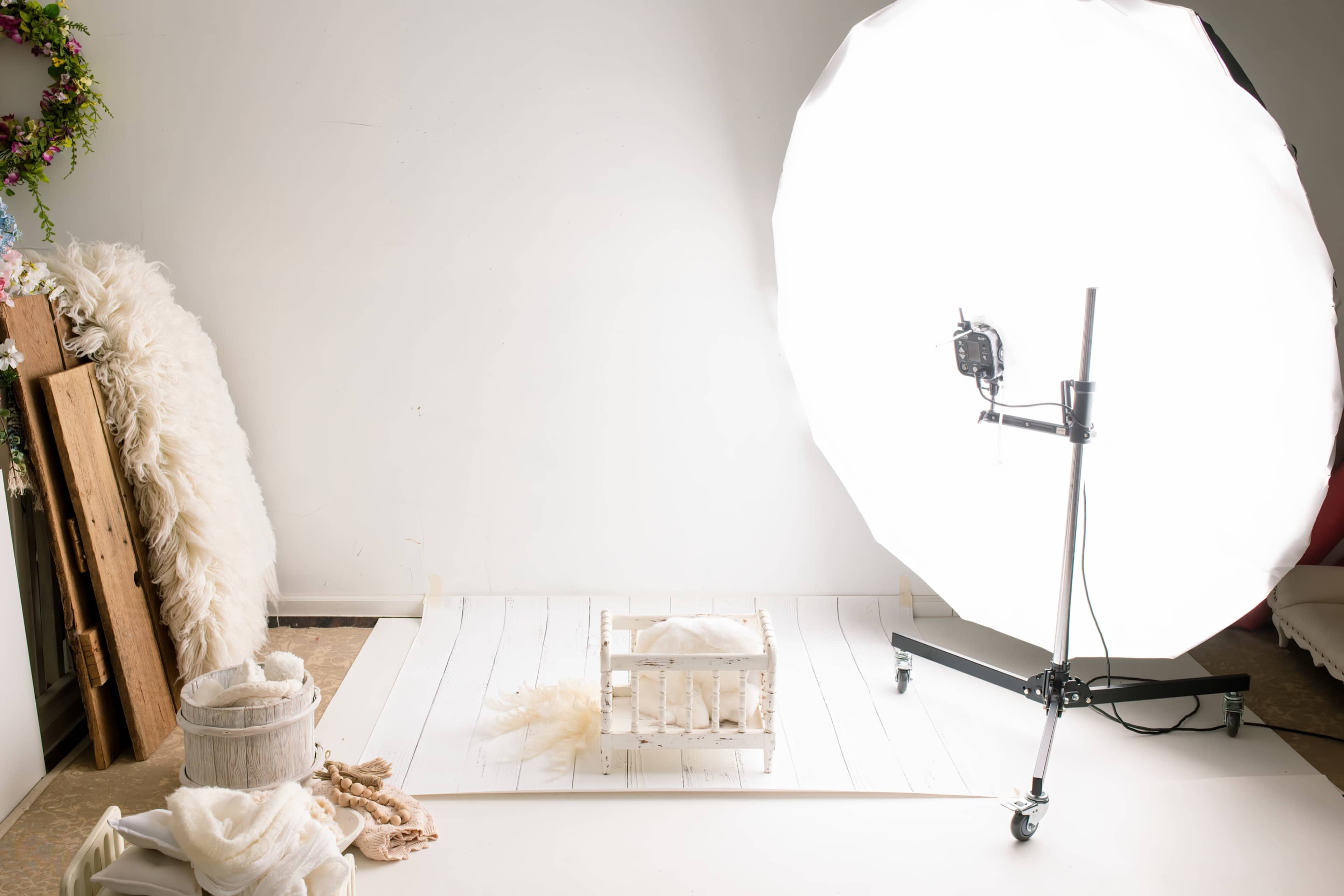 The image shows a photography studio setup with a large softbox light and a wooden crate on a white backdrop.