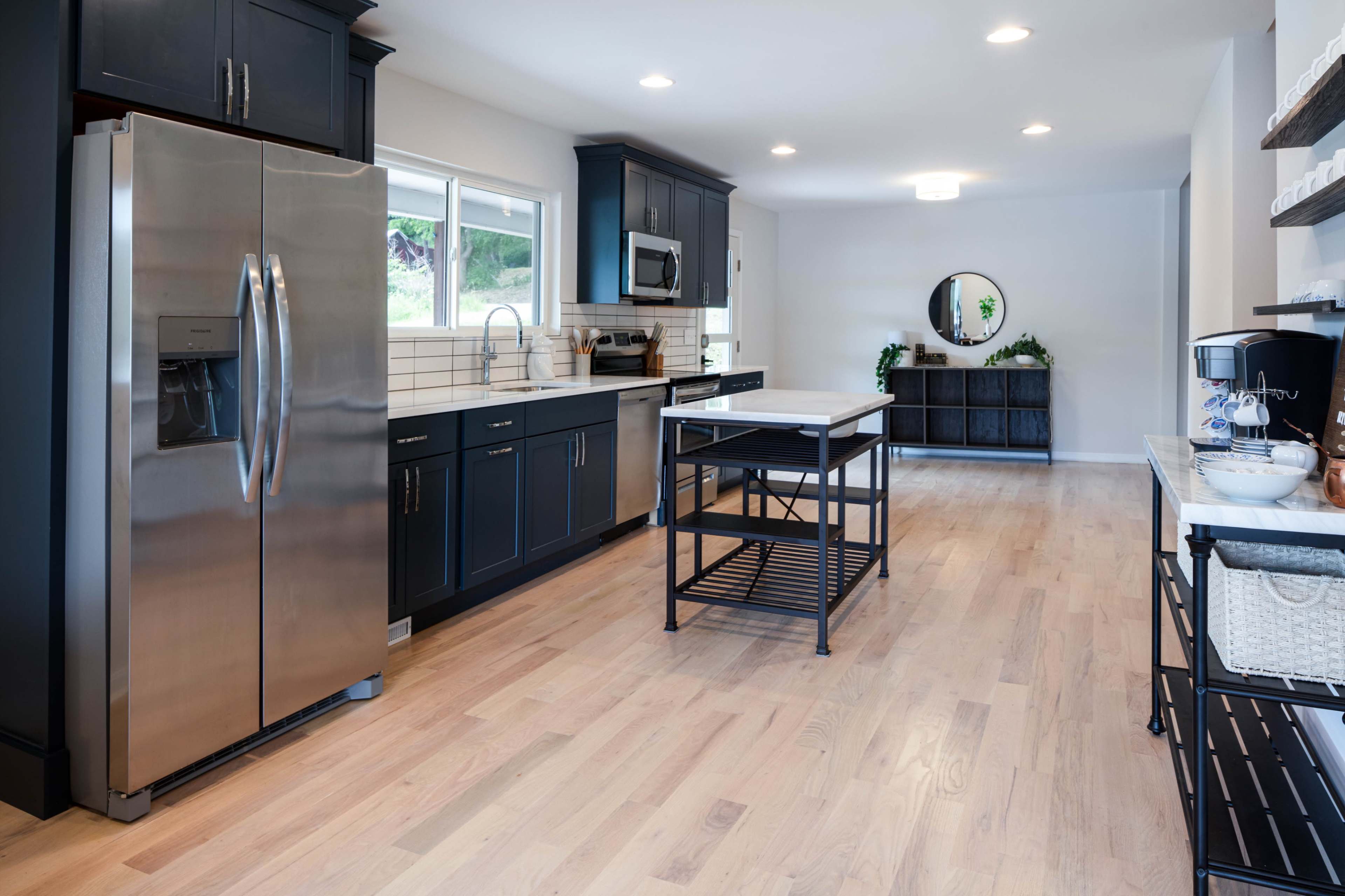 A modern kitchen featuring stainless steel appliances, dark cabinetry, and a central island with a light wood countertop.