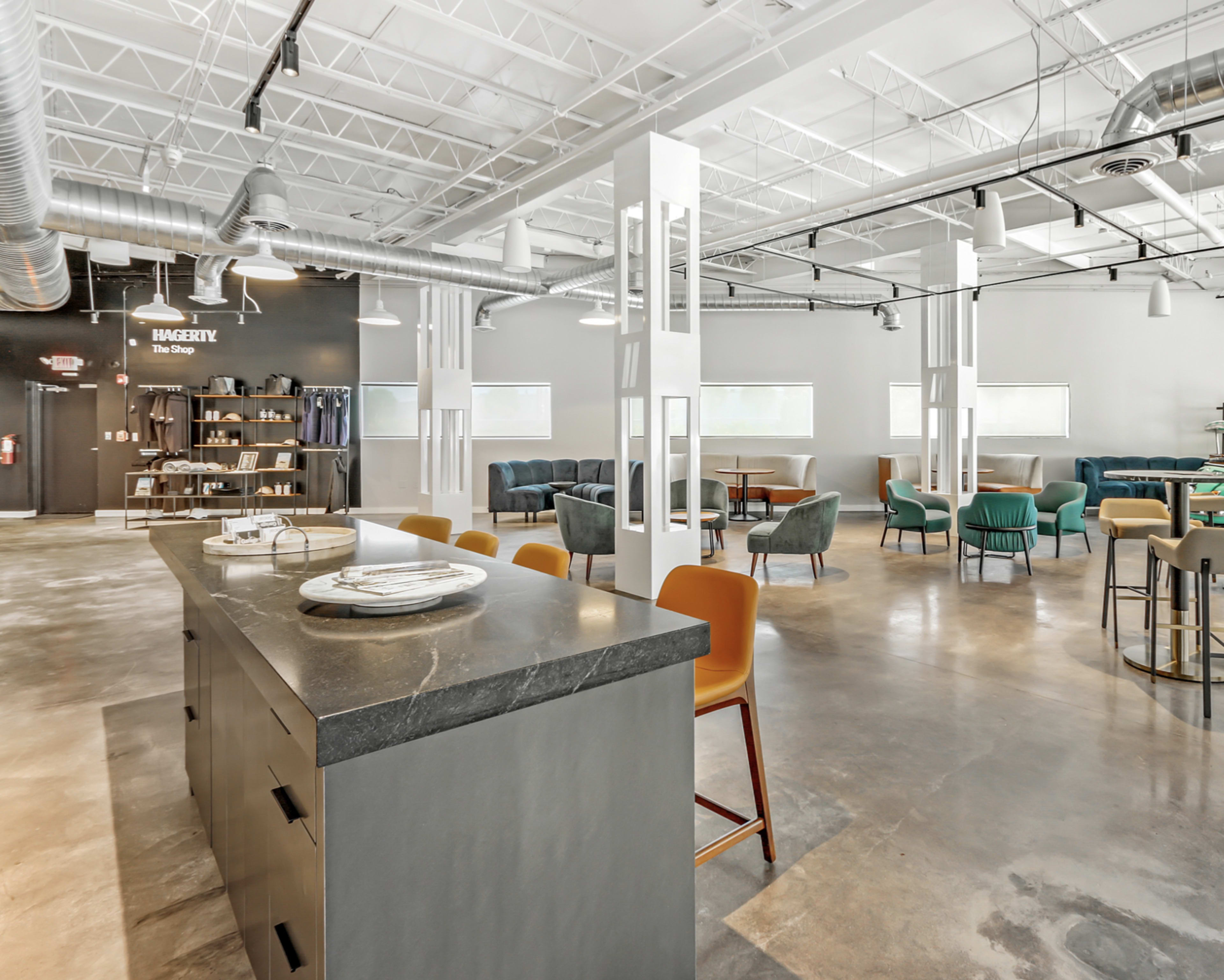 A spacious, modern open area with seating arrangements, a bar with a dark countertop, and large windows allowing natural light.