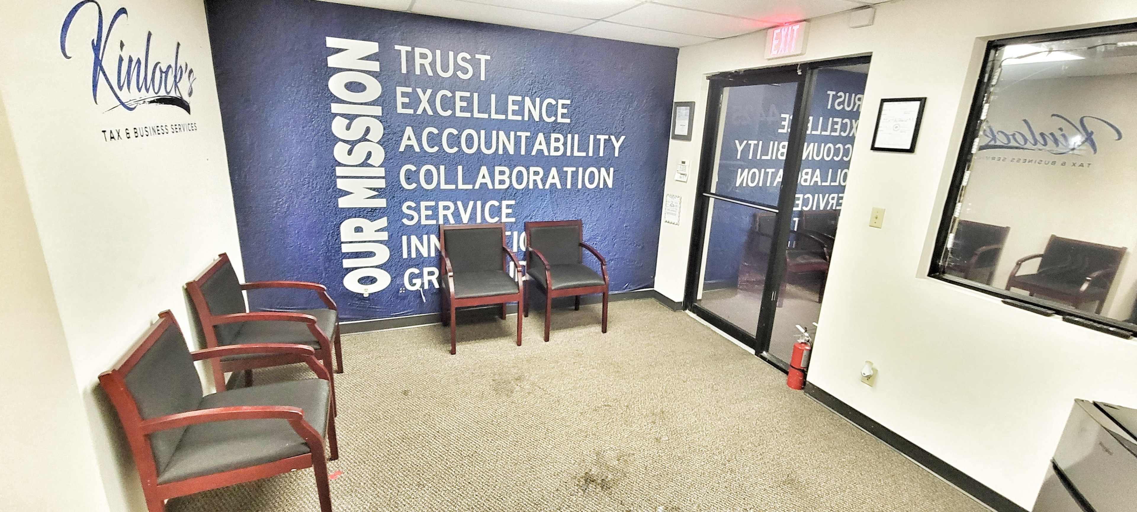 A waiting area features four chairs, a wall with a motivational message, and a glass door leading outside.