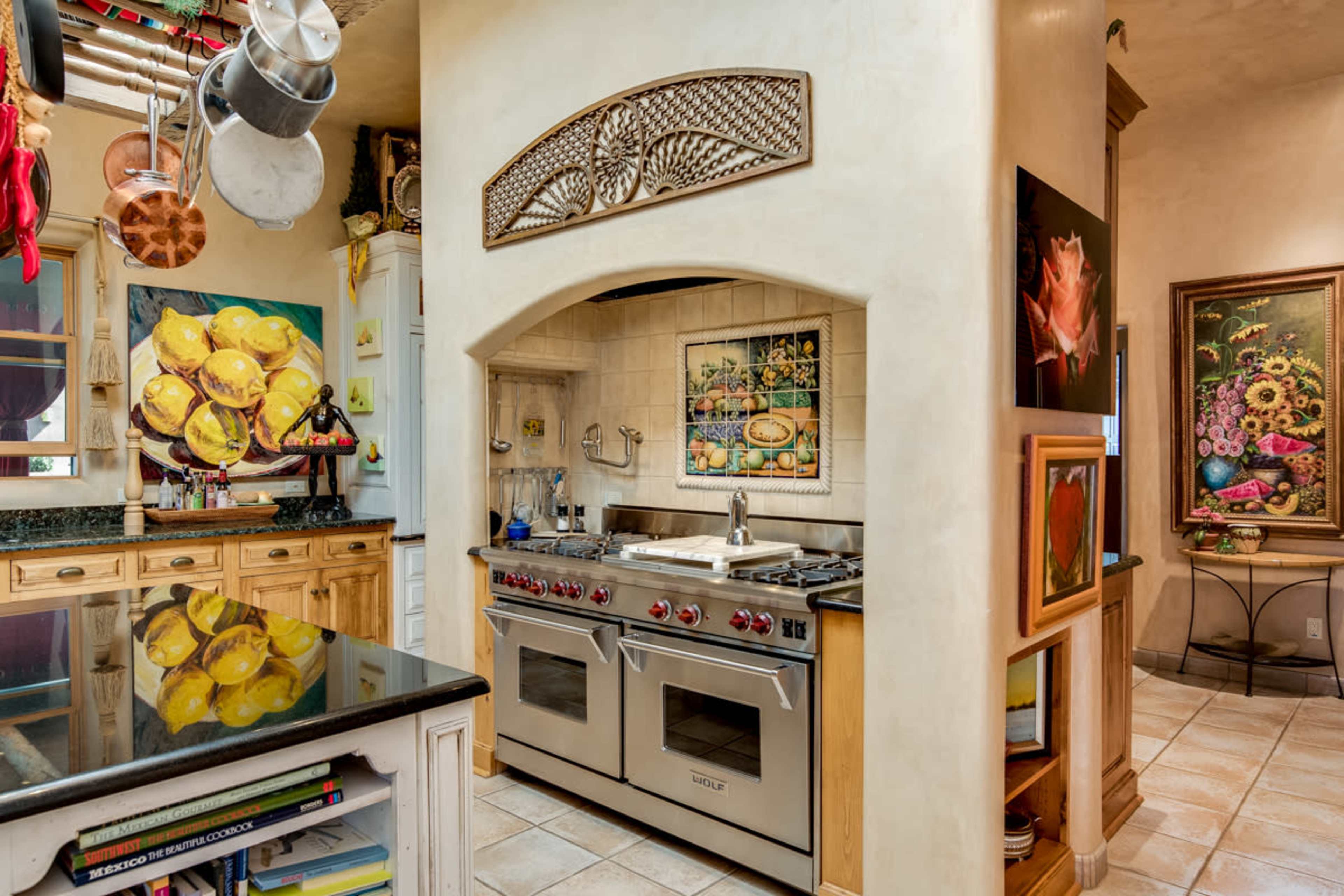 A kitchen with a stainless steel stove, a decorative archway, and colorful artwork on the walls.