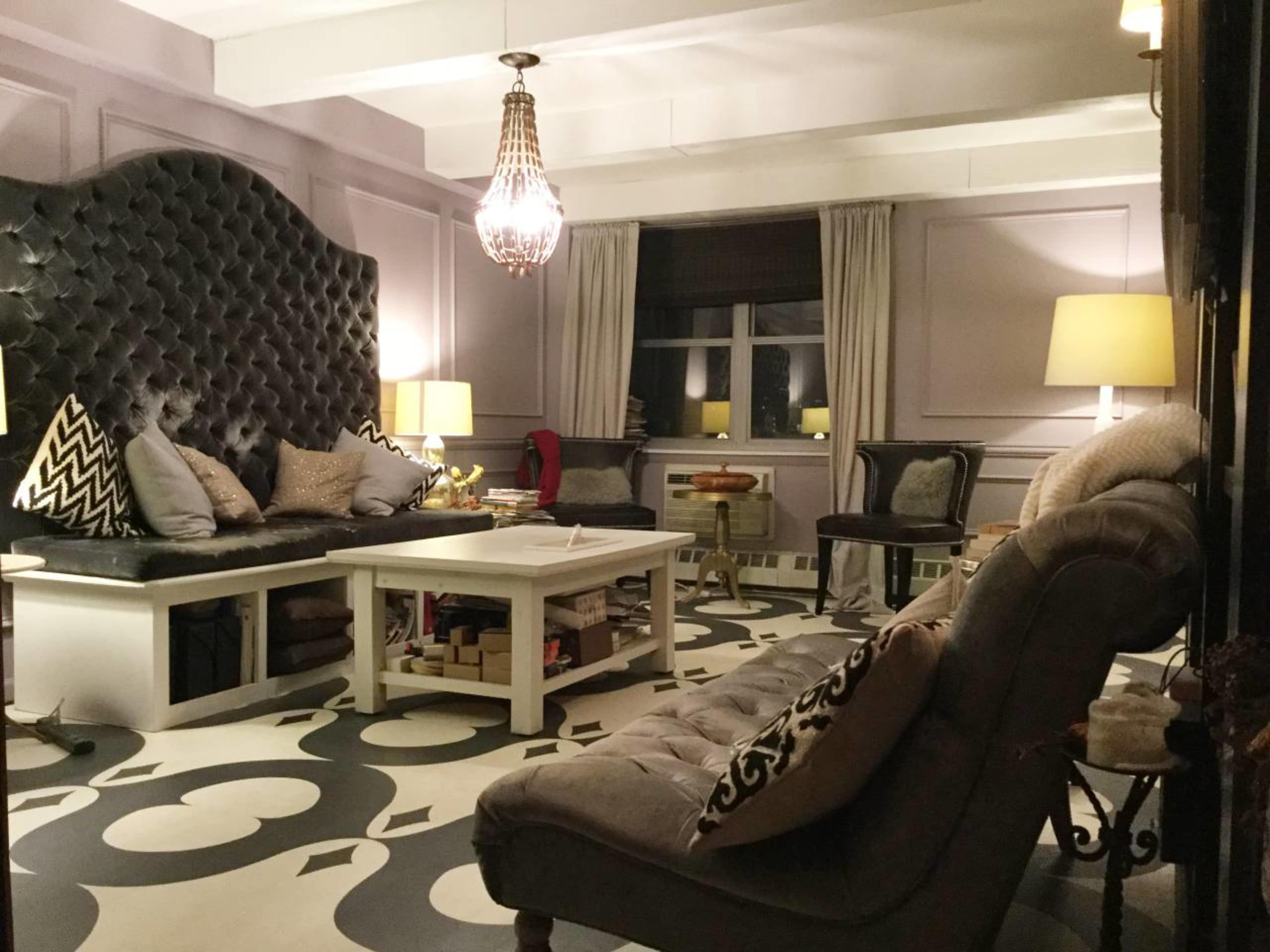 A stylish living room with a large tufted black sofa, a central white coffee table, and decorative lamps providing soft illumination.