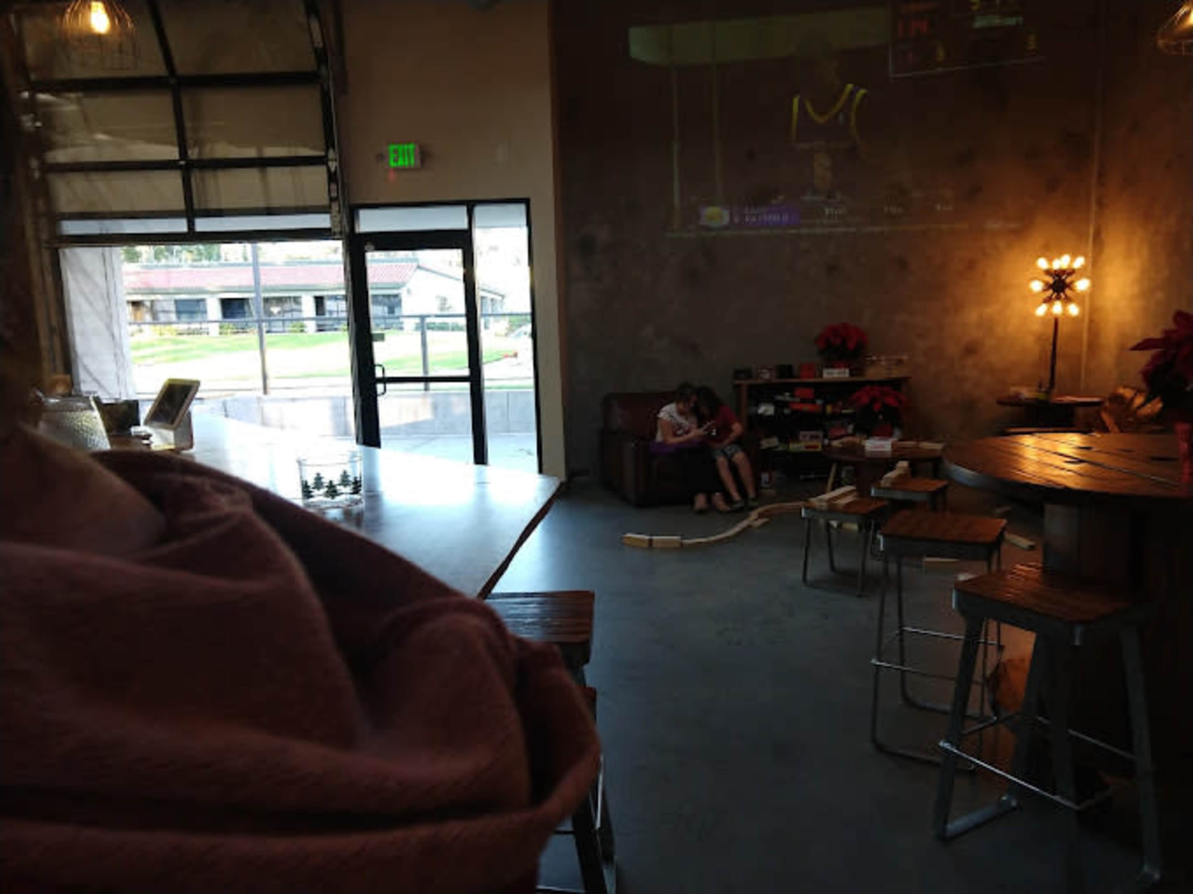 A child sits on a couch in a café, while a large screen displays a sports game in the background.