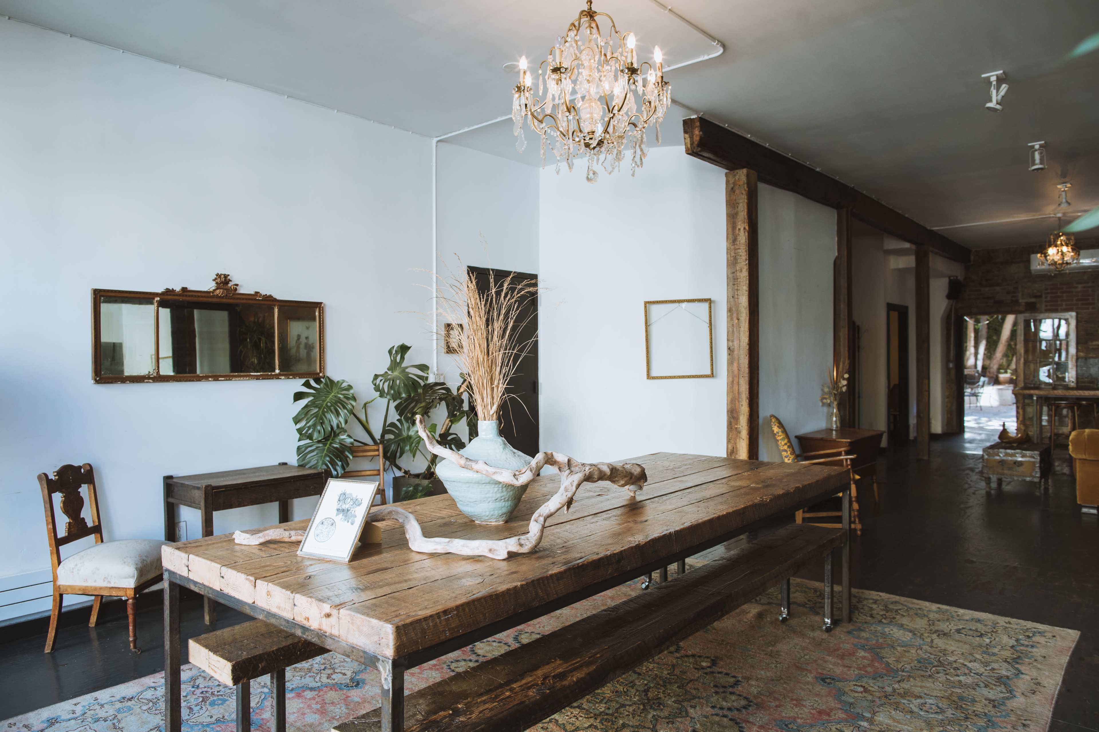 A spacious interior with a large wooden table at the center, surrounded by various pieces of vintage furniture and décor.