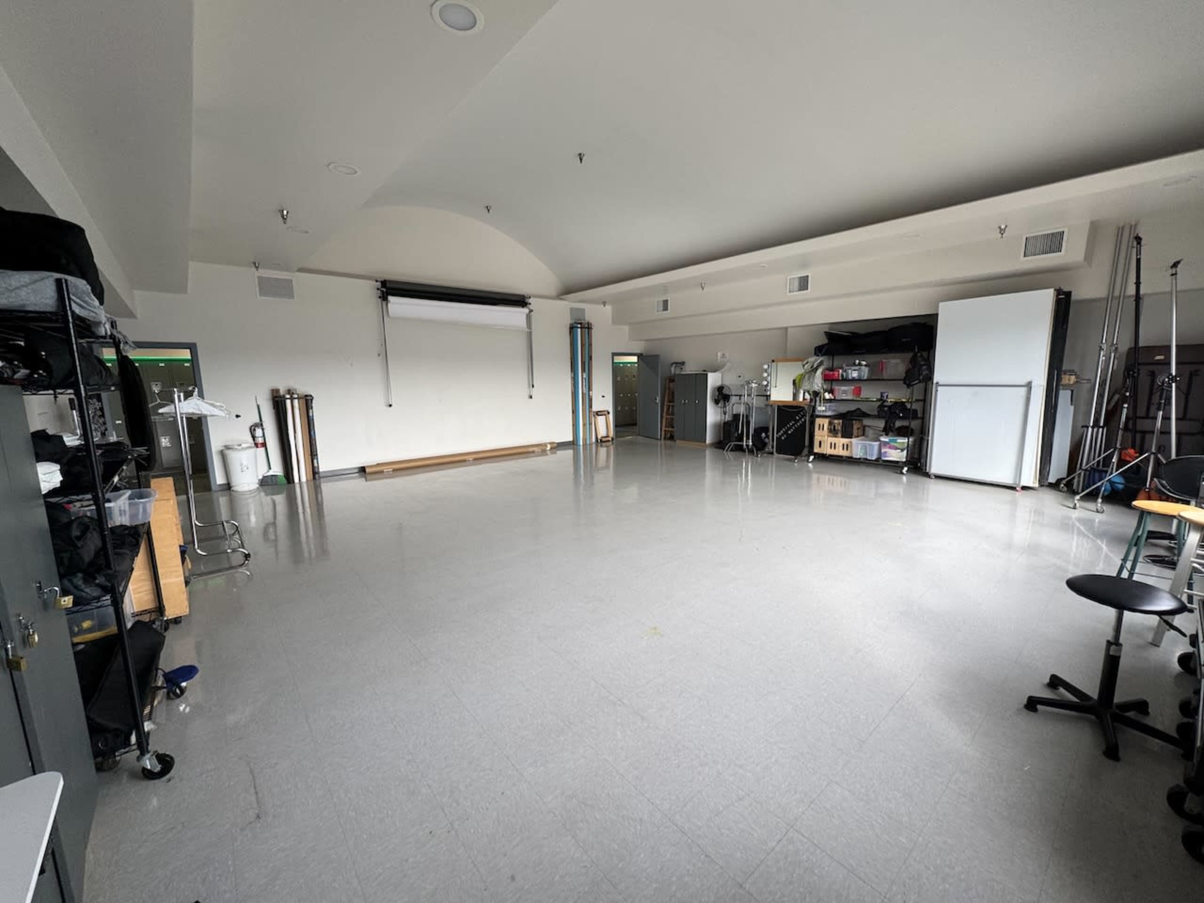 The image shows an empty room with gray tile flooring, white walls, and various storage units along one side.