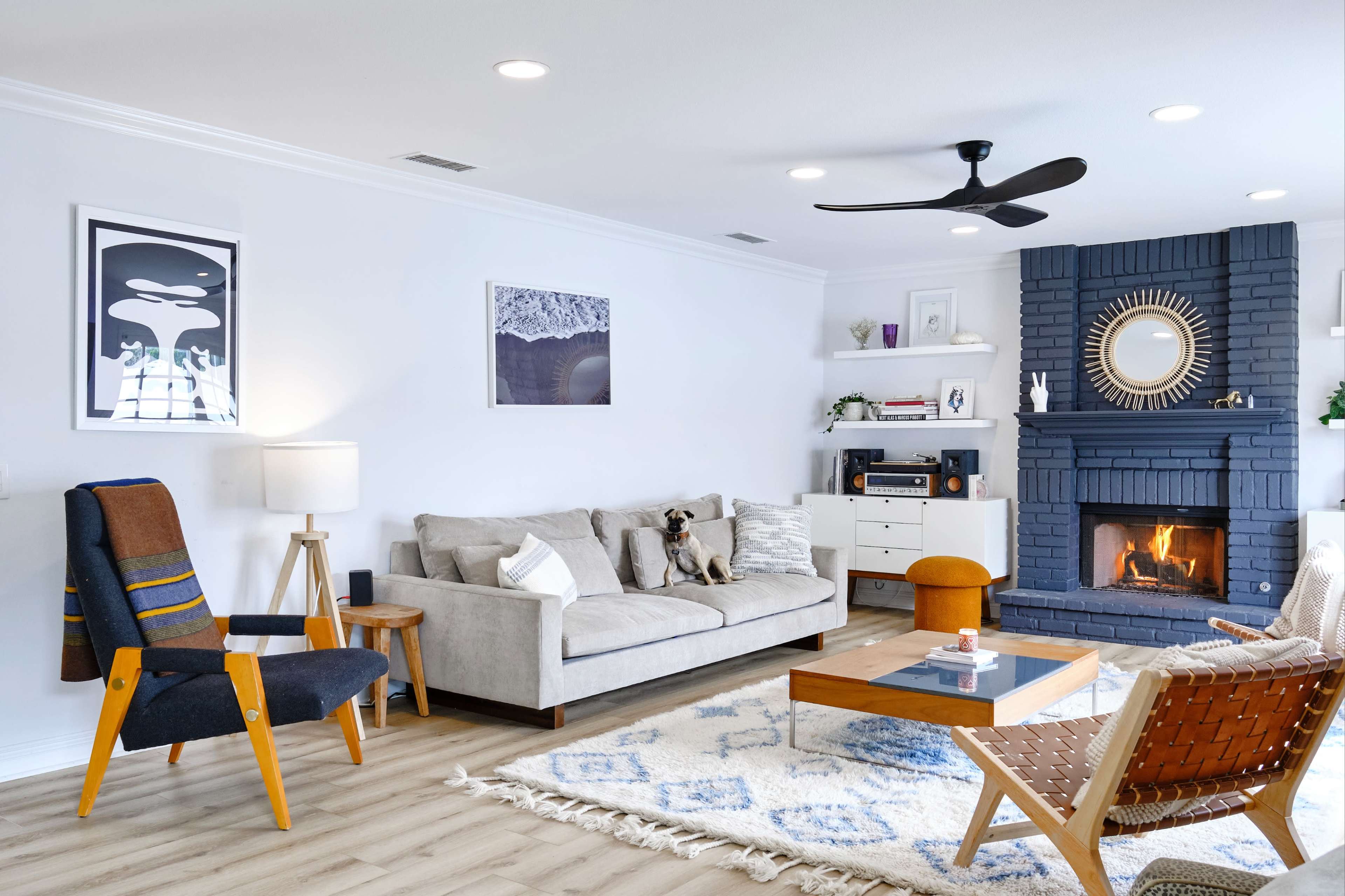 The living room features a gray sofa, a wooden coffee table, and a fireplace with a modern chair and a neatly arranged rug.