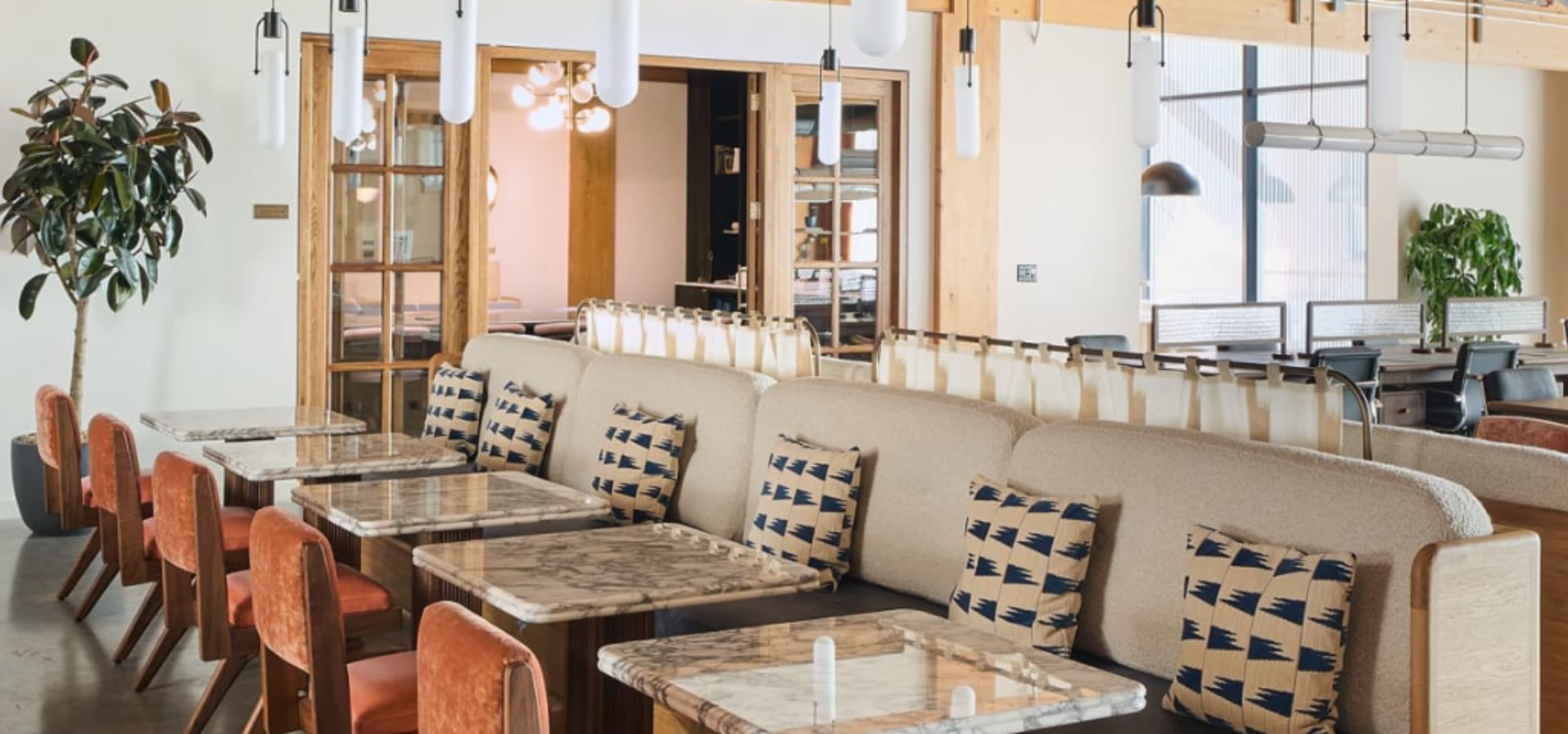 A modern restaurant interior featuring a plush seating area with marble-topped tables and decorative cushions.