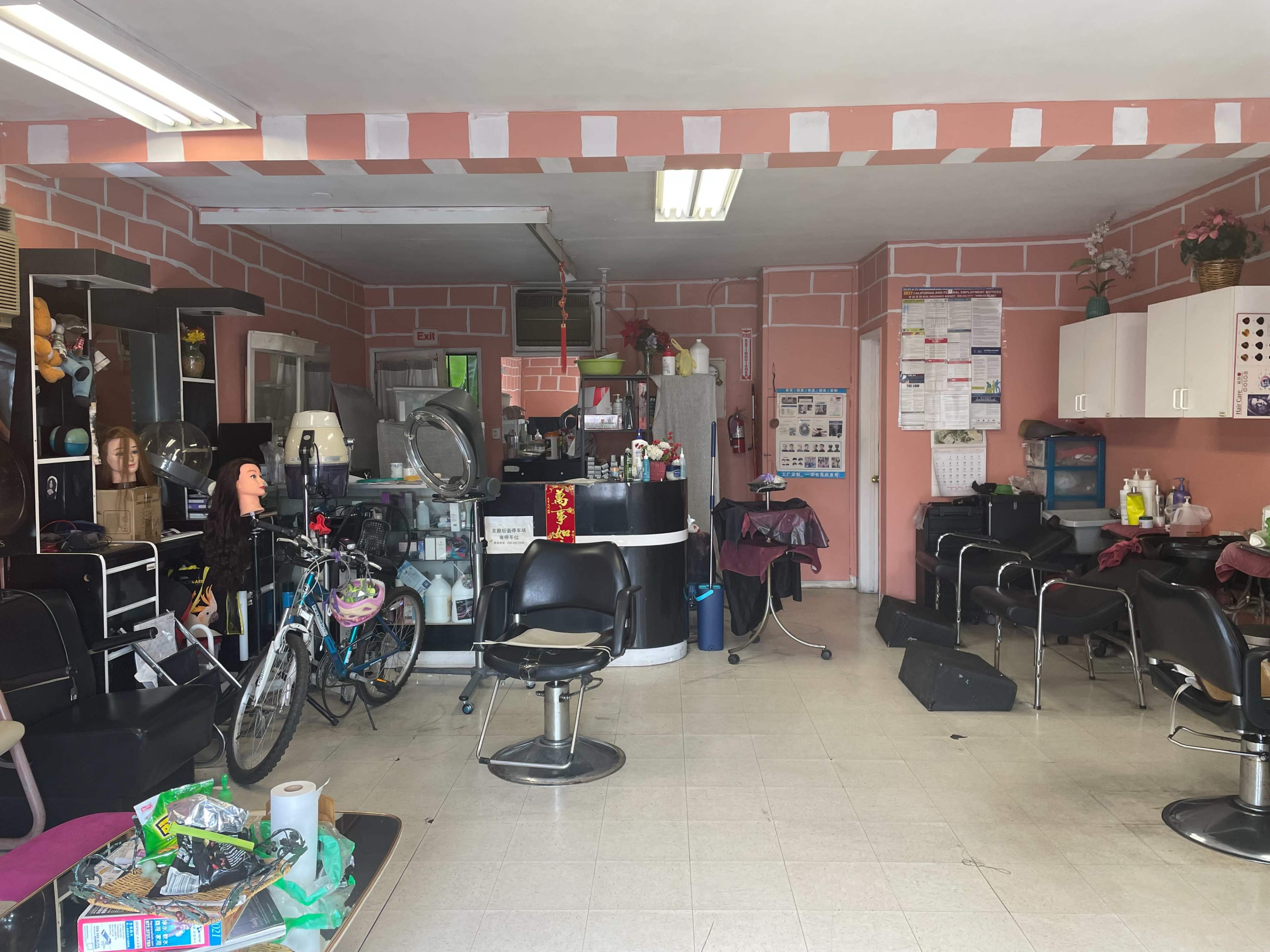 The interior of a hair salon with styling chairs, a reception area, and various beauty supplies scattered throughout.