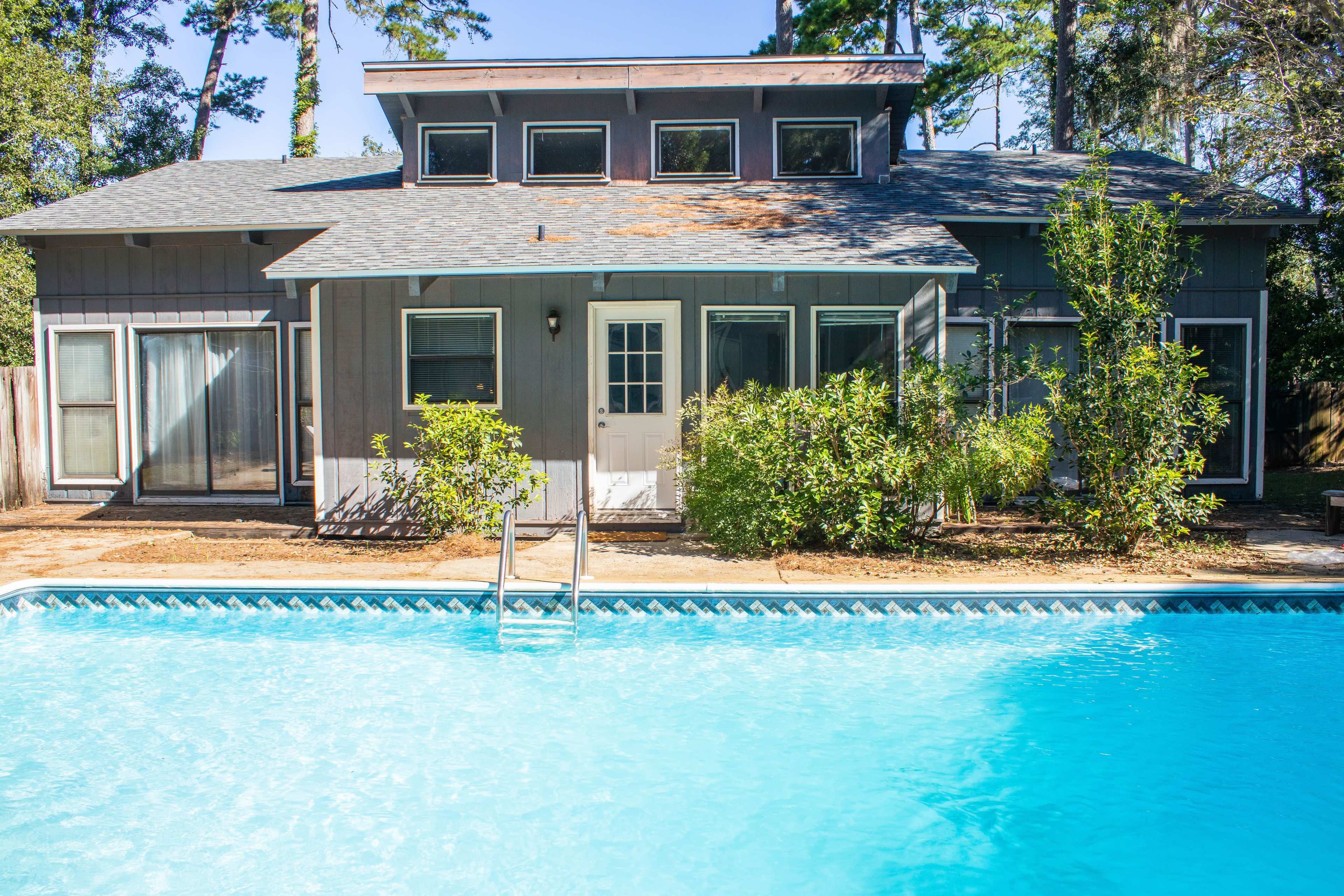 A two-story house with large windows and a swimming pool in the front yard.