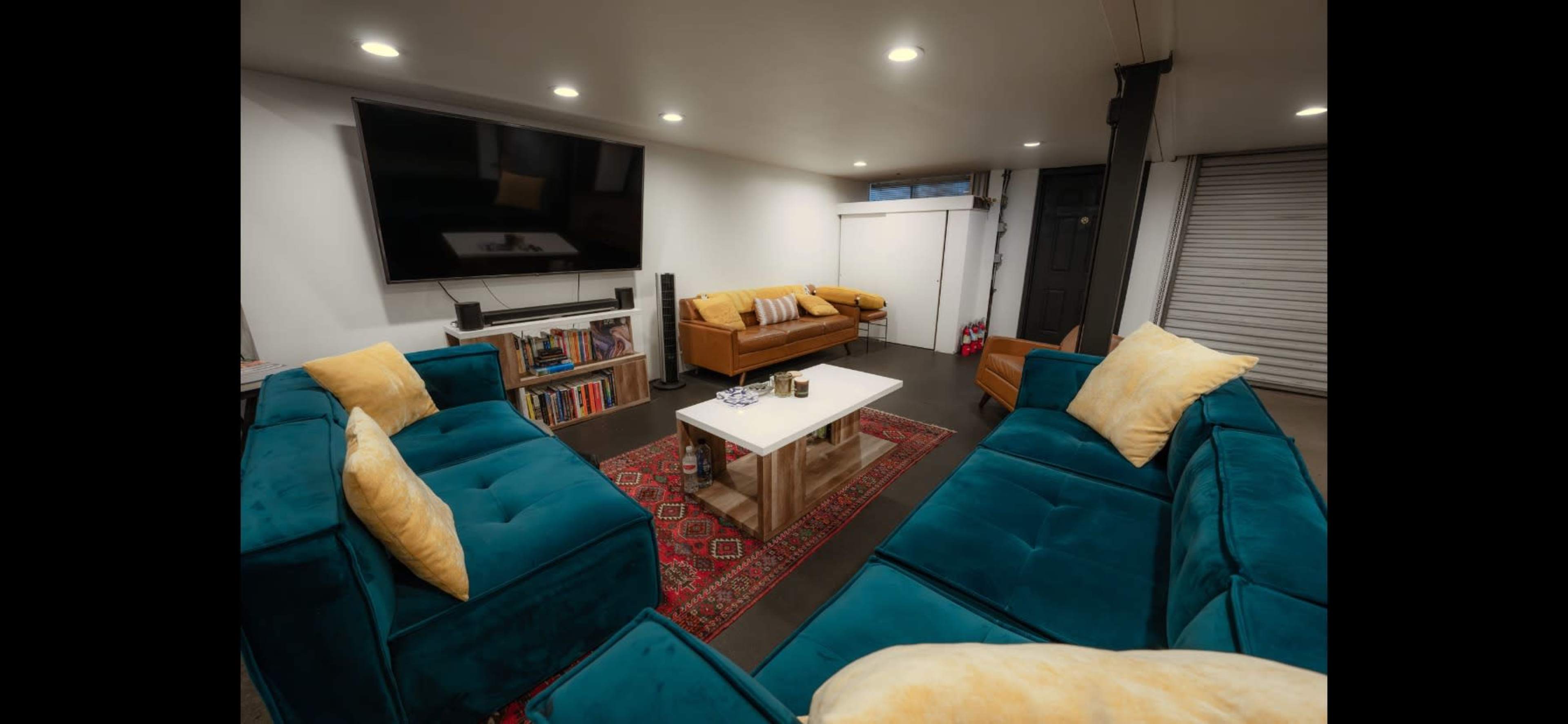 A modern living room with teal sectional sofas, a coffee table, and a mounted television.