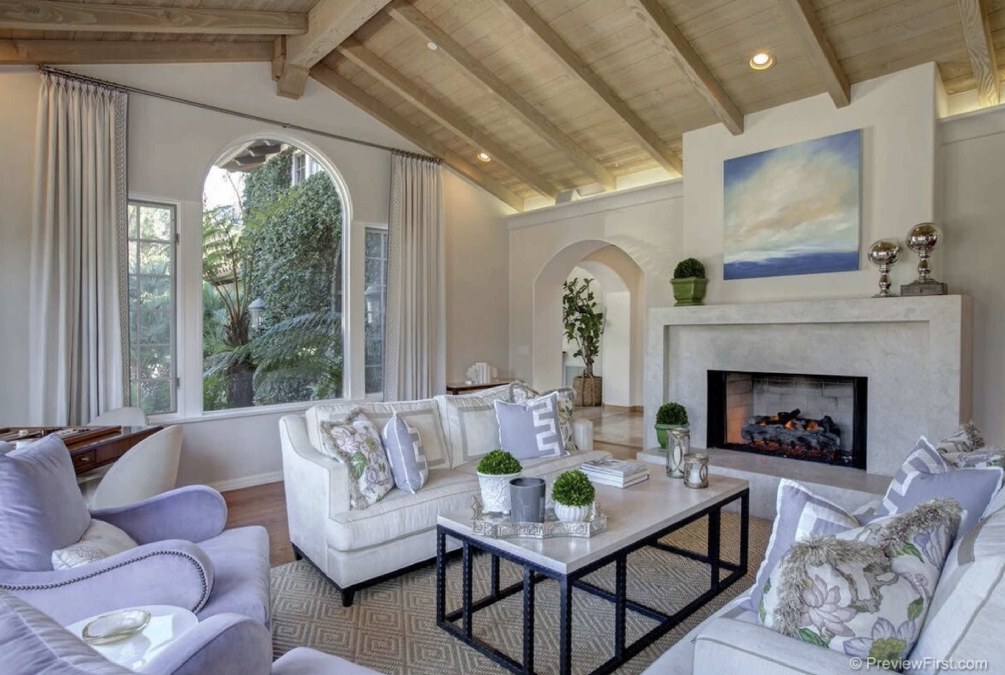 The living room features a vaulted ceiling, large windows, a fireplace, and a mix of comfortable seating arrangements.