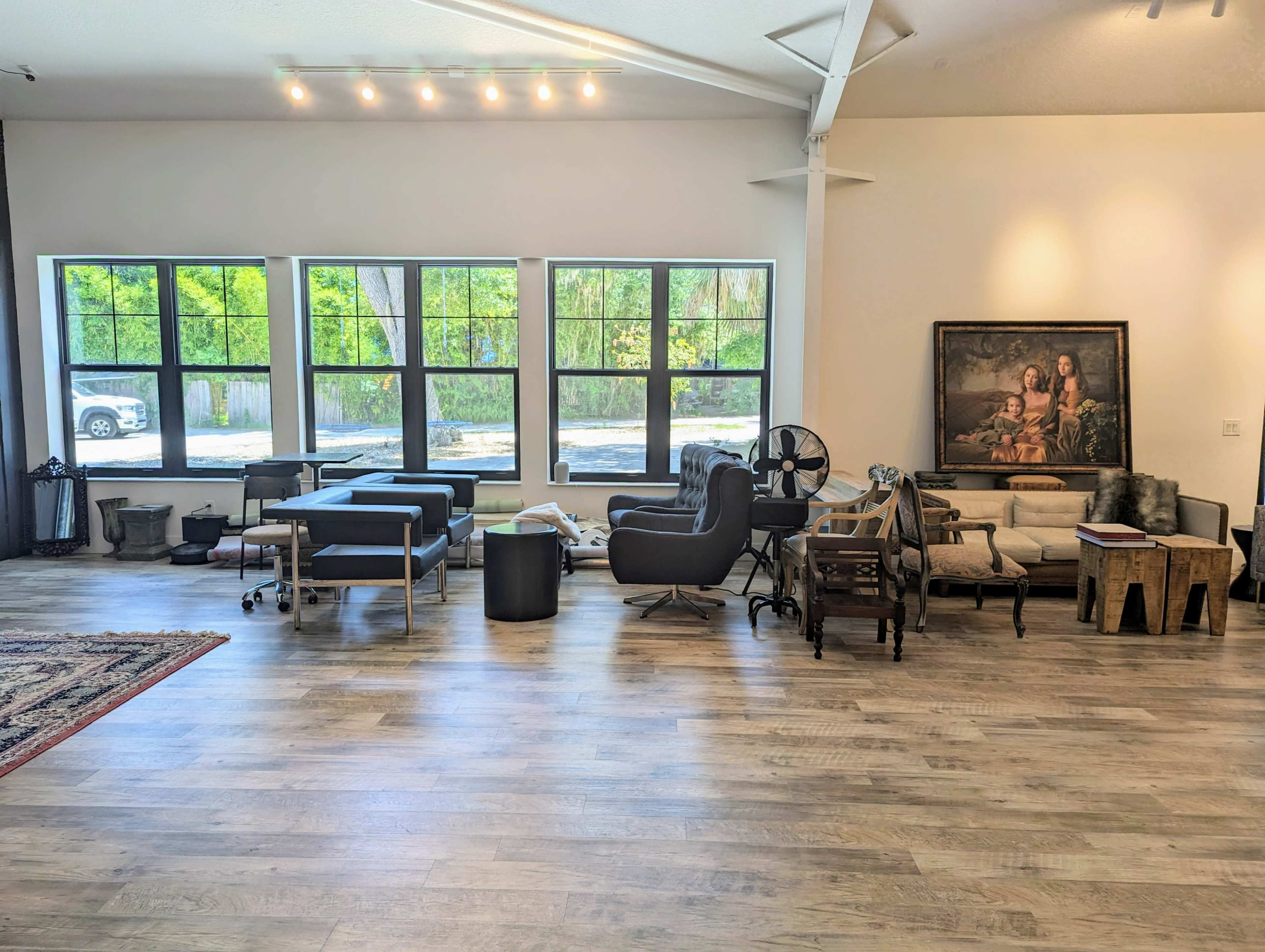 A spacious interior with a variety of furniture pieces arranged near large windows, providing ample natural light.