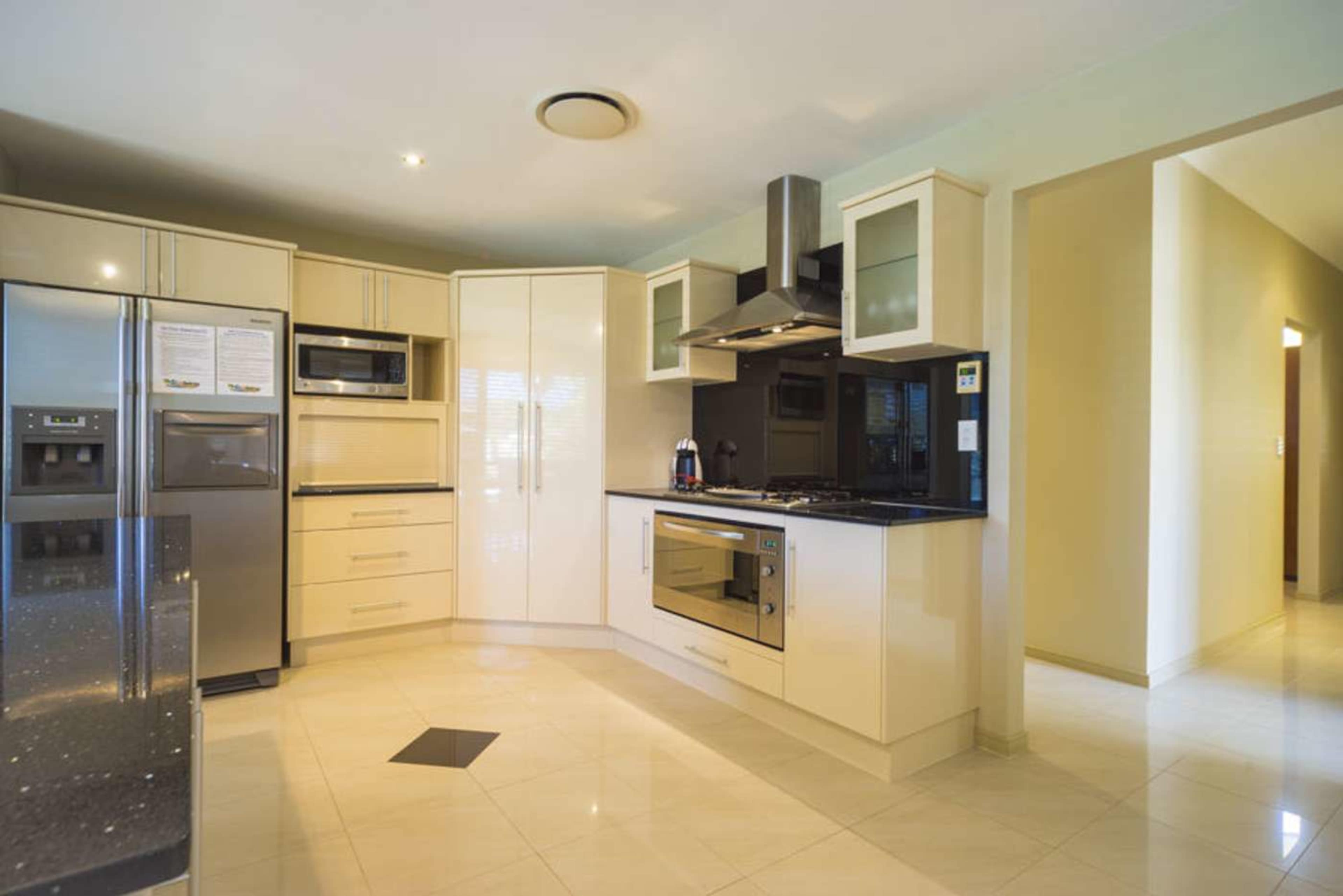 The kitchen features sleek cabinetry, stainless steel appliances, and a tiled floor.