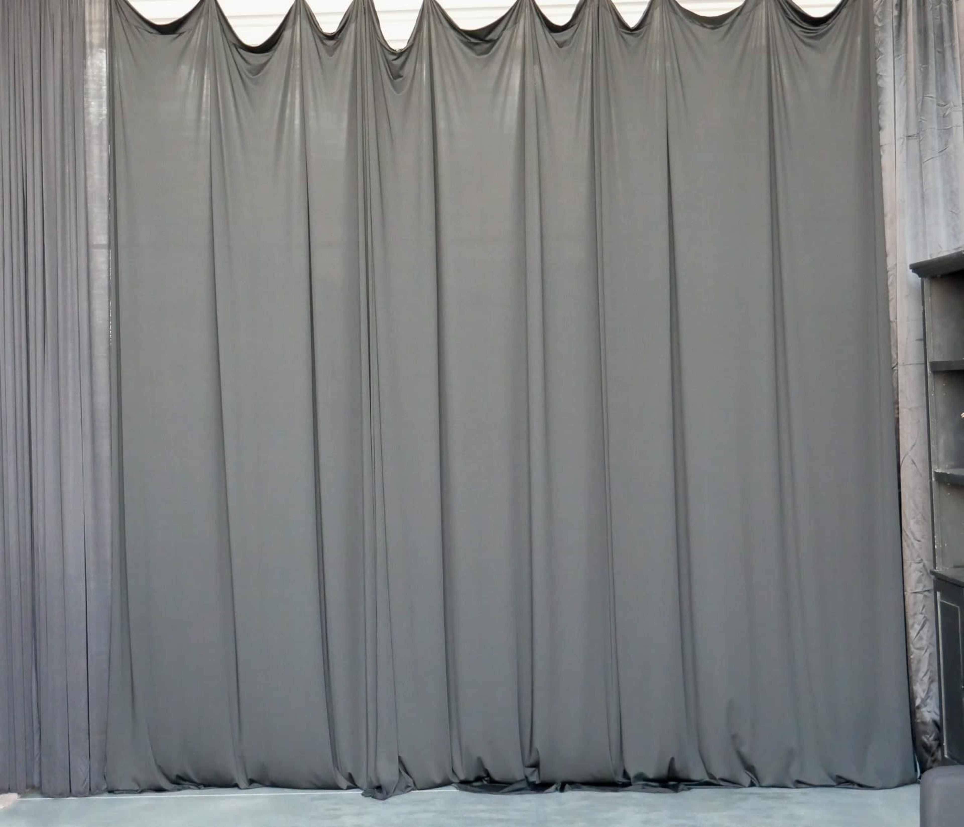A series of gray drapes arranged in folds with a smooth texture.