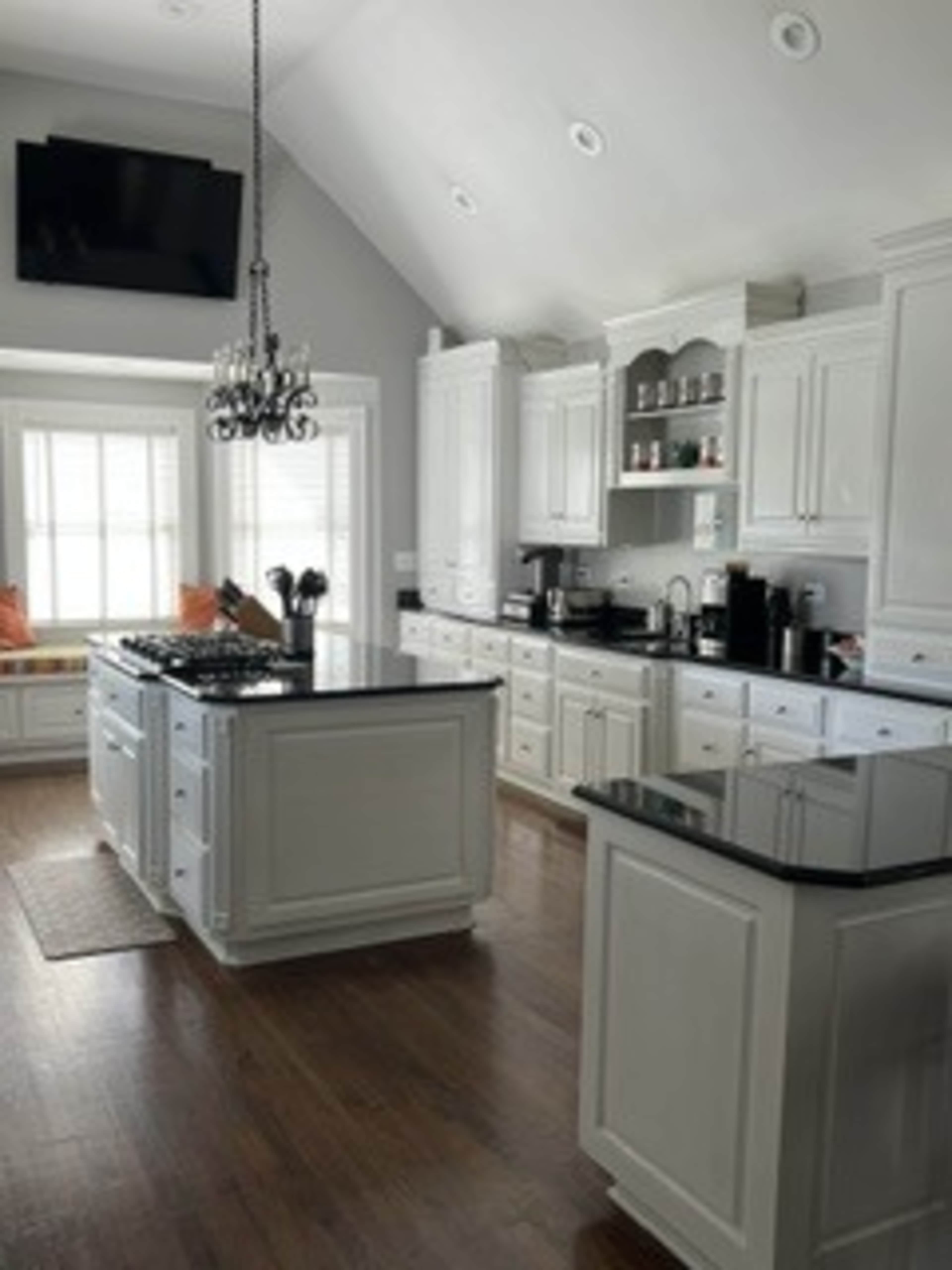 The kitchen features white cabinetry, a large island with a gas stove, and a cozy window seat, illuminated by natural light.