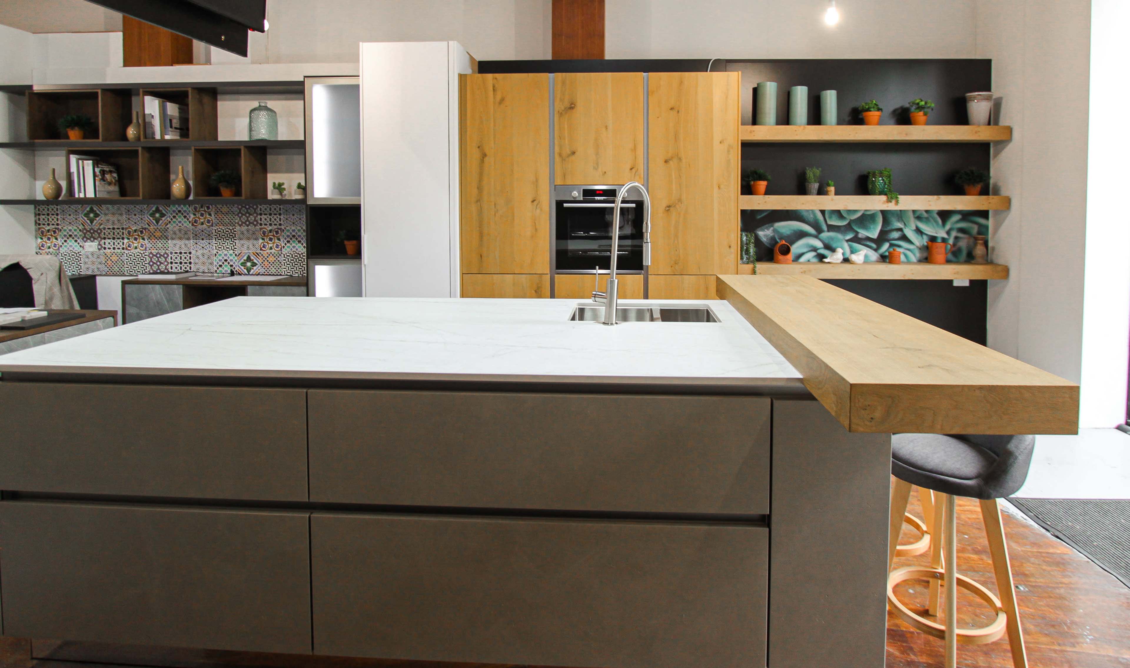 The image shows a modern kitchen featuring an island with a marble countertop, wooden accents, and sleek cabinetry.