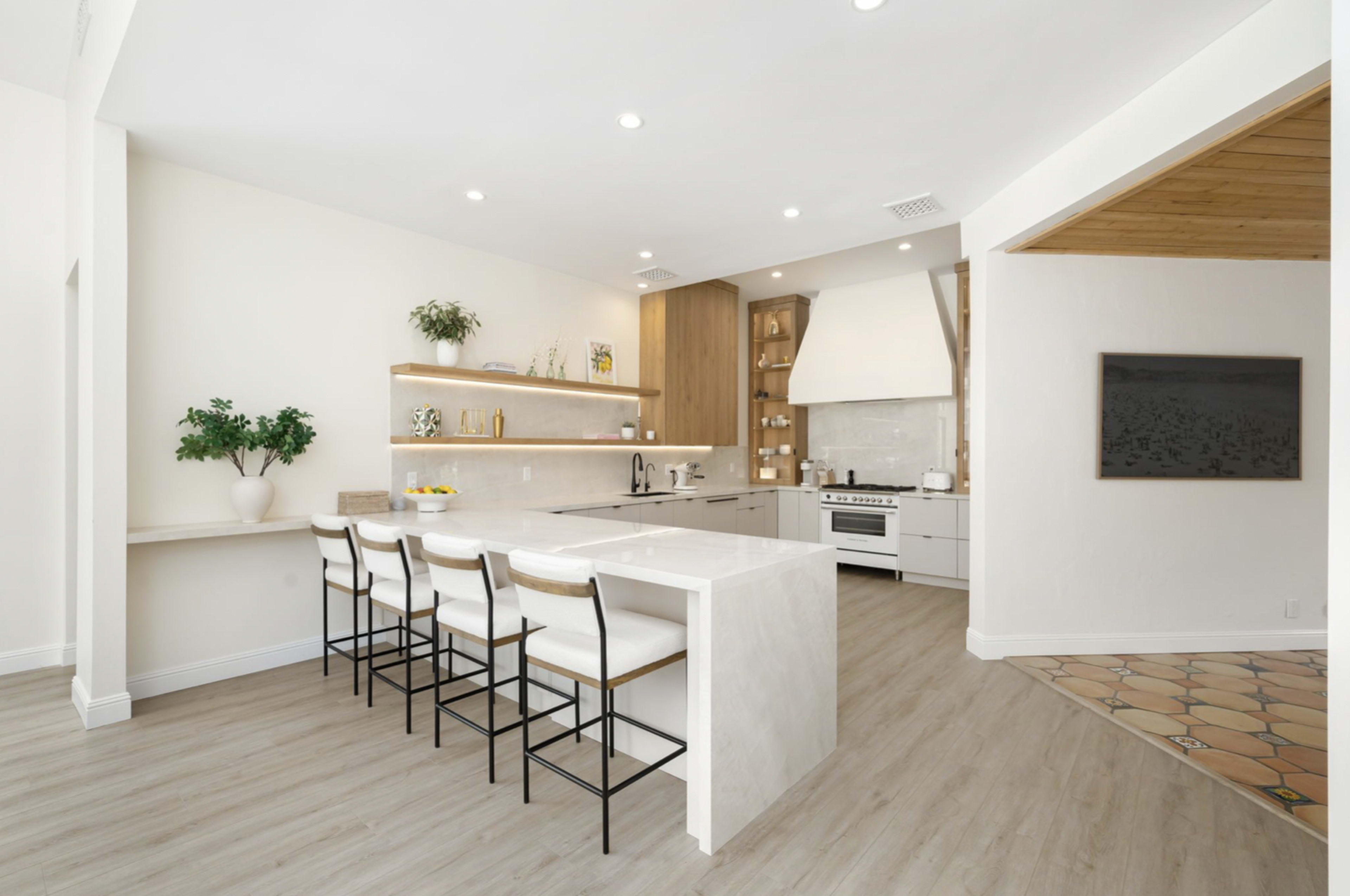 The image showcases a modern kitchen featuring a center island with bar seating, wooden cabinetry, and bright lighting.