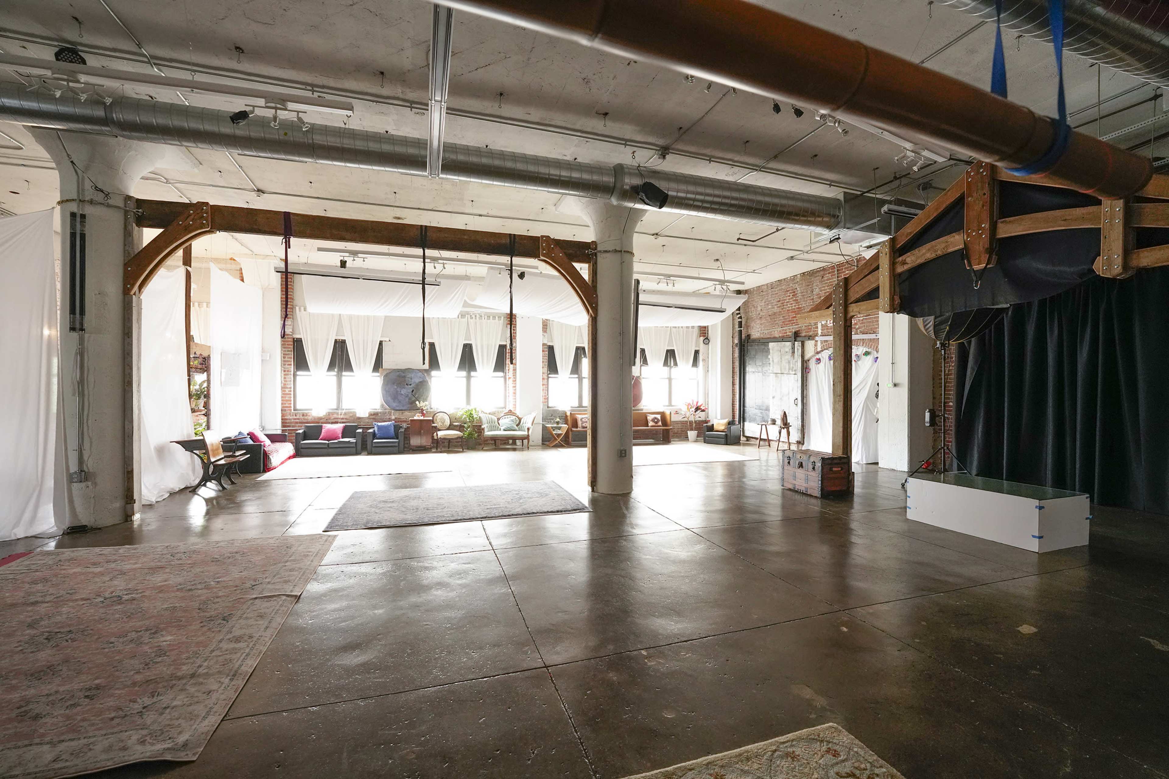 The spacious interior features exposed beams, large windows, and a variety of seating areas with decorative elements.