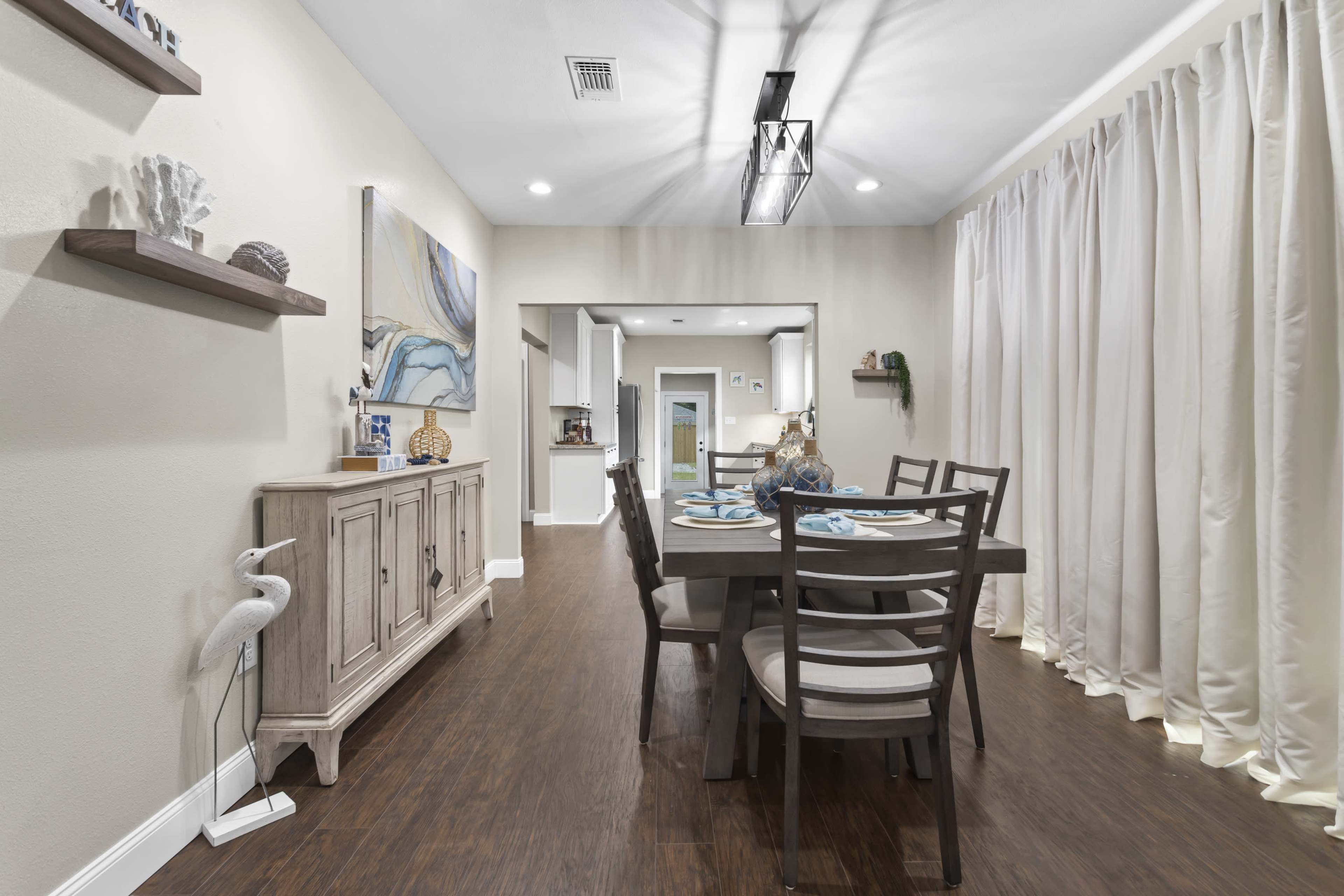A dining area featuring a wooden table set for a meal, surrounded by chairs, with a sideboard and decorative shelves on the walls.