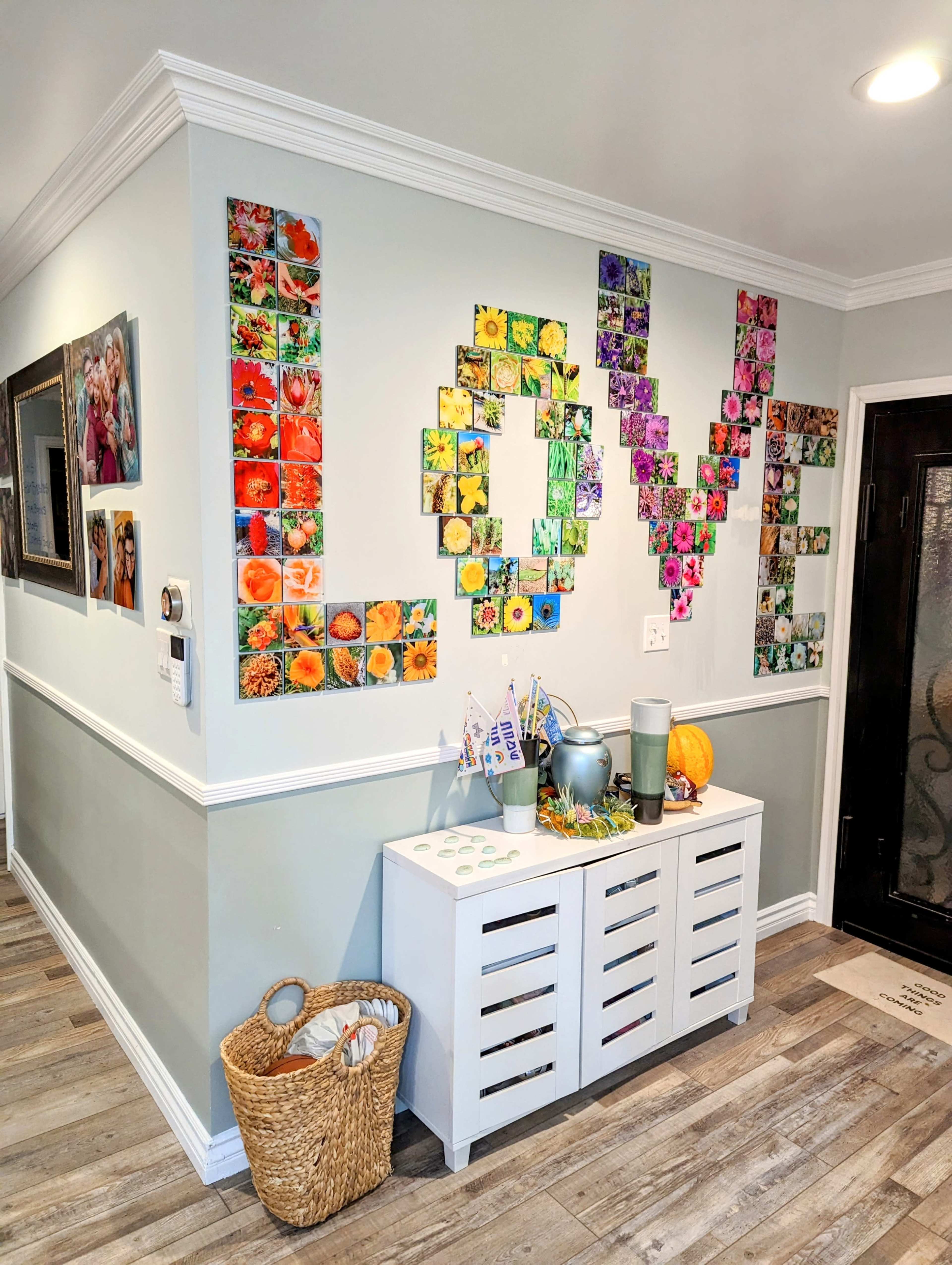 A wall is decorated with a colorful arrangement of photographs forming the word "LOVE," accompanied by a console table displaying various items.