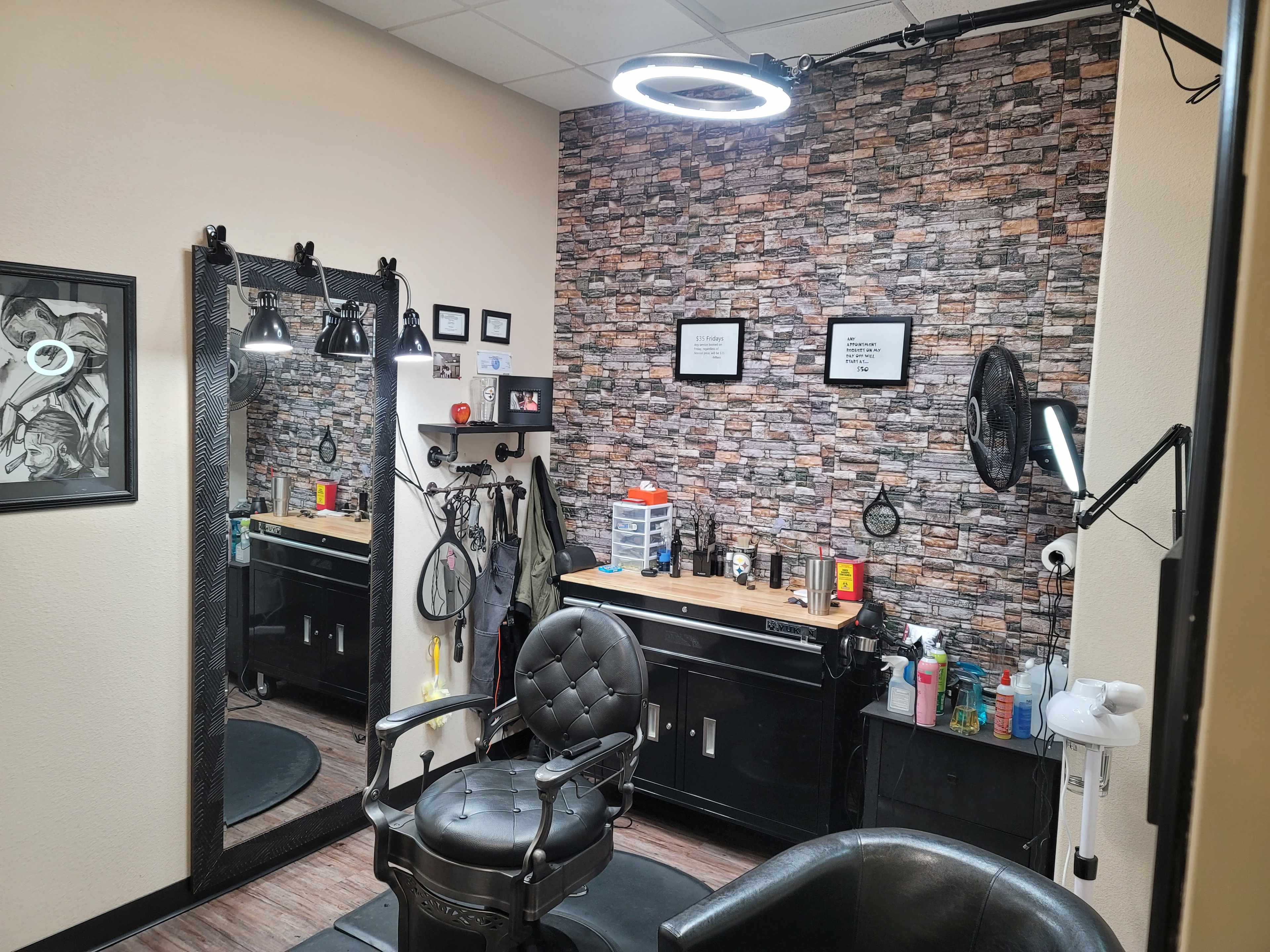 A small hair salon with a black barber chair, a large mirror, and a stone-patterned accent wall, equipped with various salon products and tools.