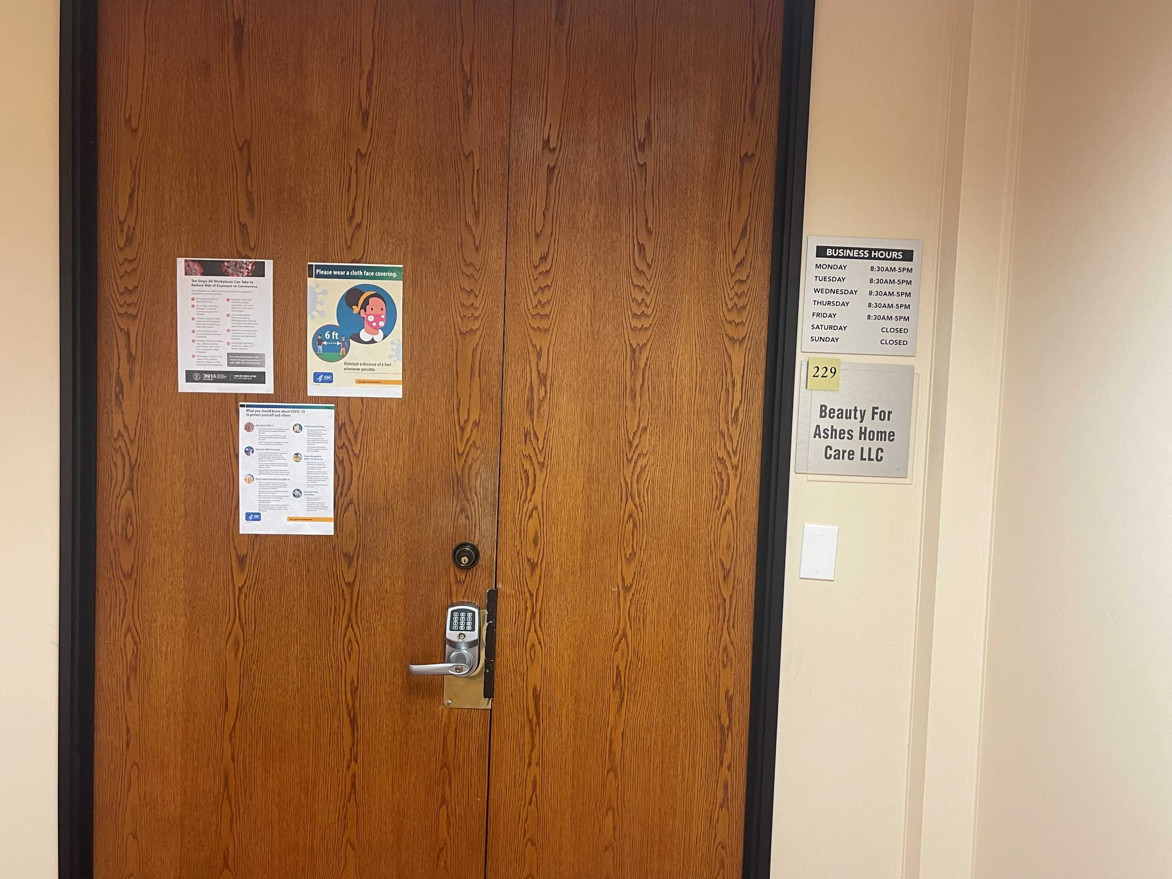 A wooden door with several flyers and a sign indicating the business name "Beauty For Ashes Home Care LLC" attached to its right side.