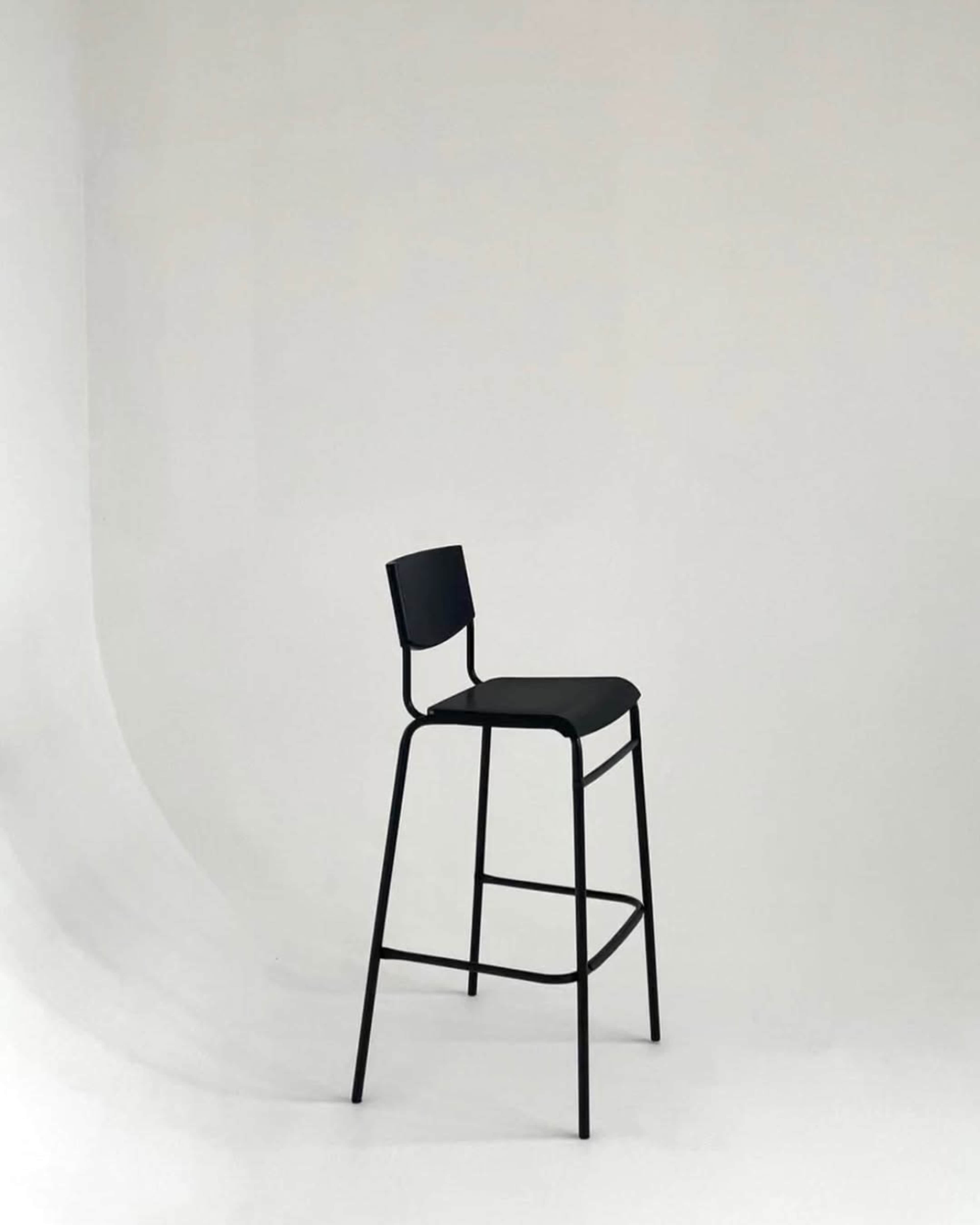 A black bar stool stands alone against a plain white background.