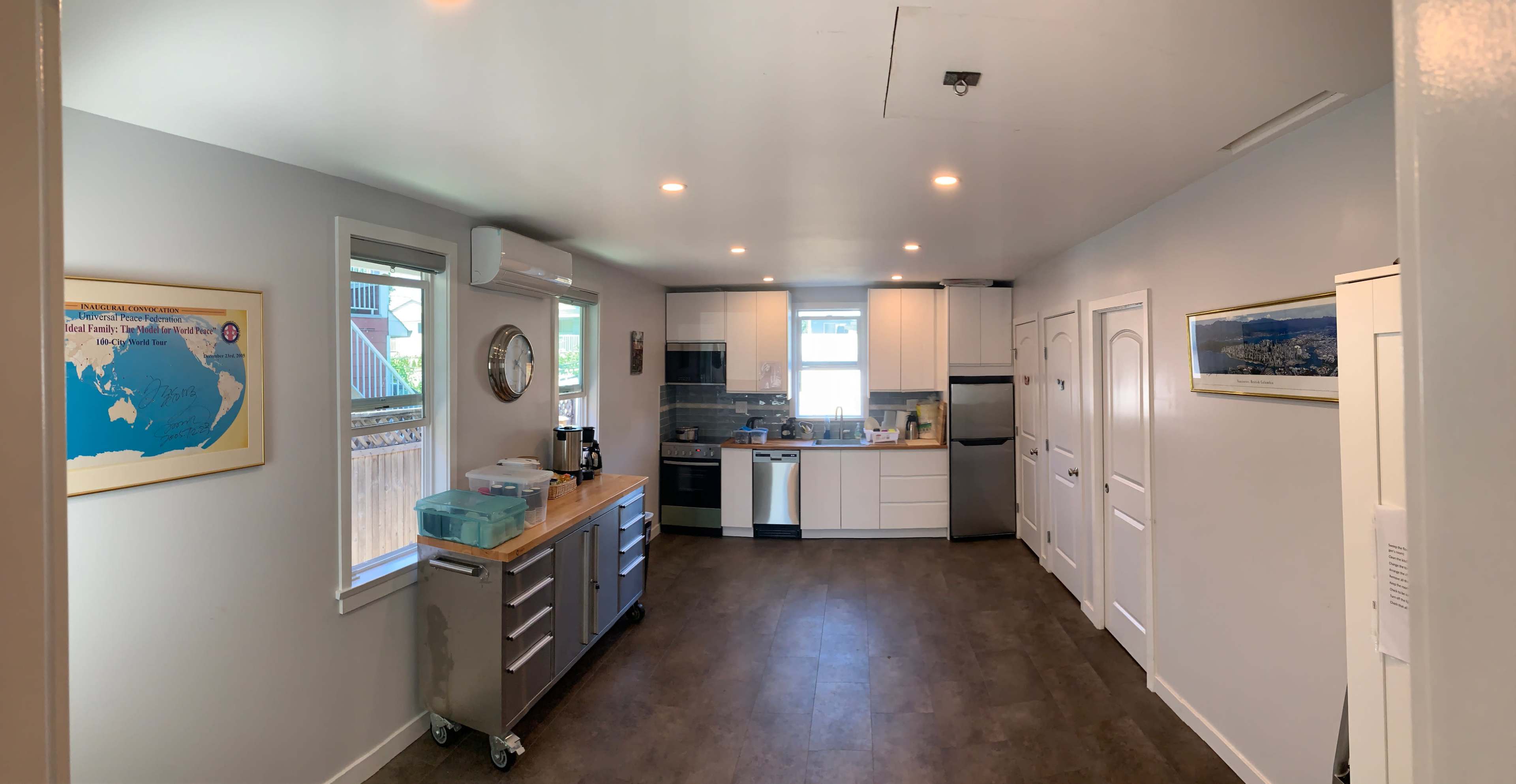A modern kitchen with white cabinets, stainless steel appliances, and a central wooden island on wheels.