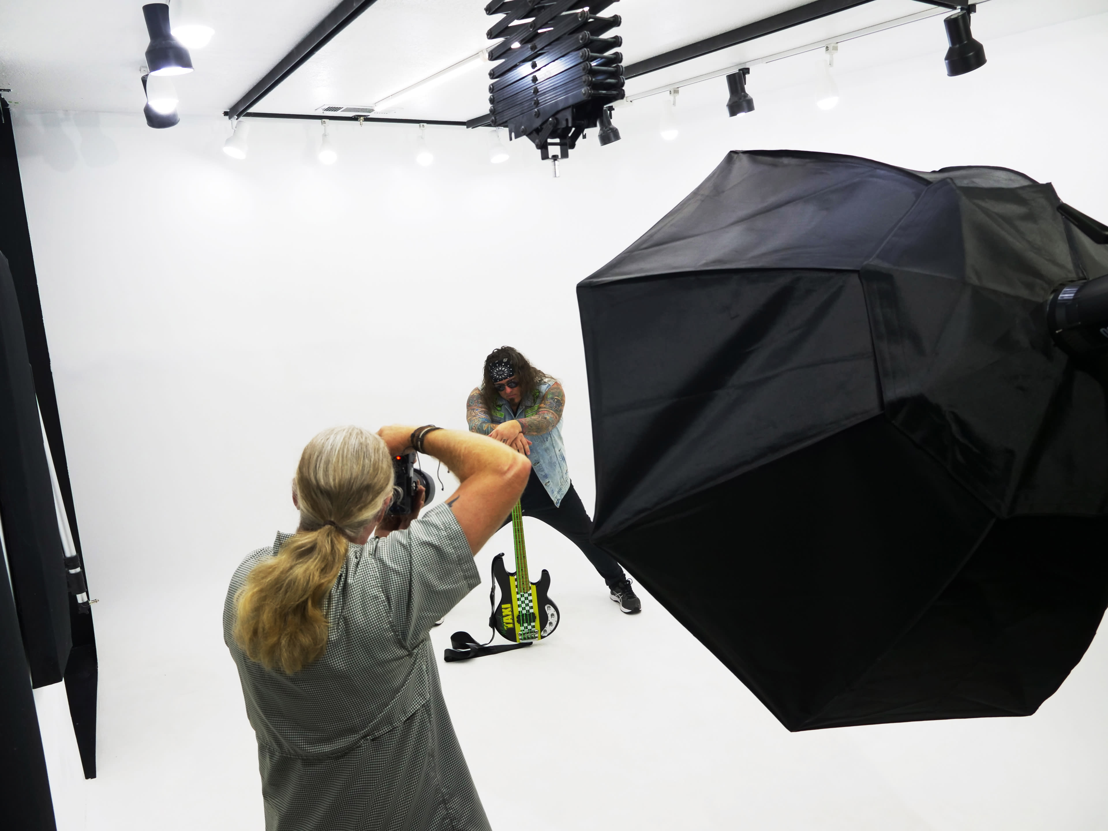A photographer captures a musician posing with an electric guitar in a well-lit studio.