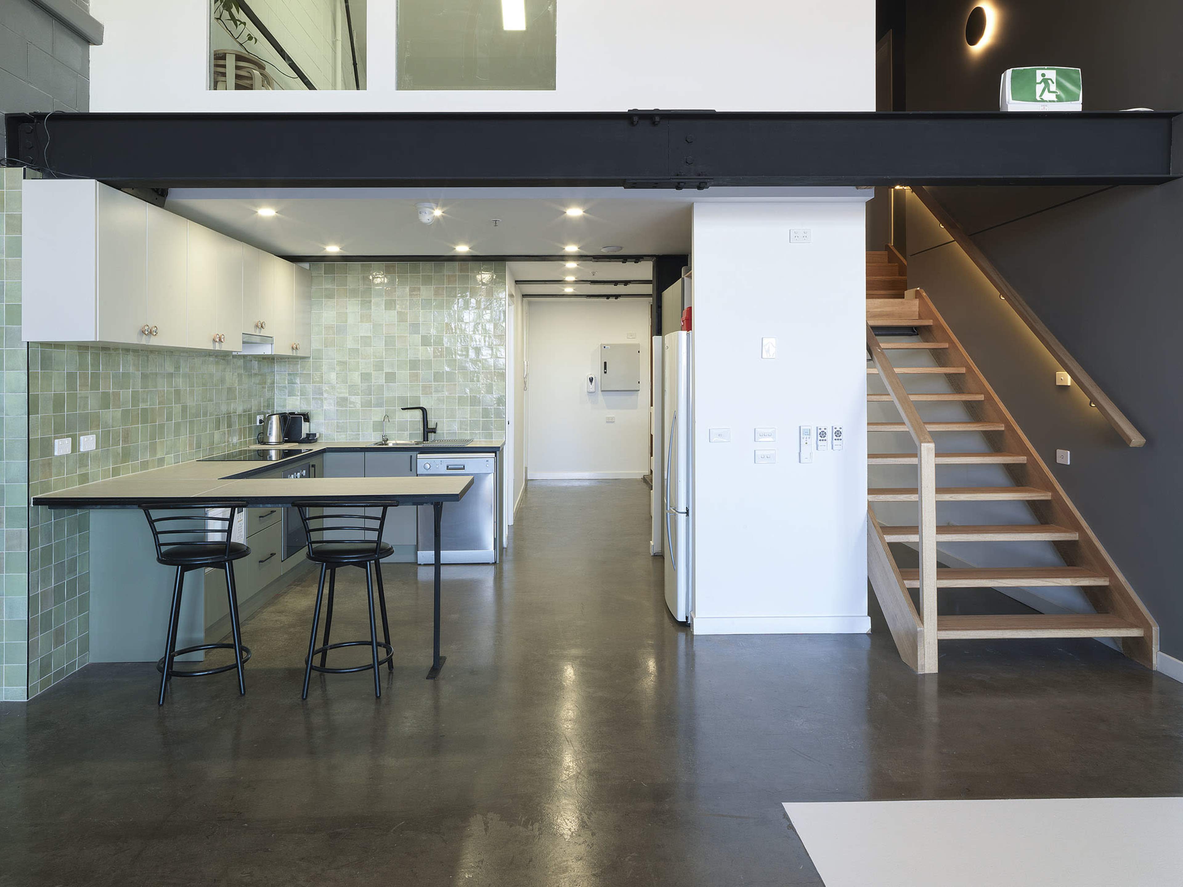 A modern kitchen with a dining area and a staircase leading to an upper level.
