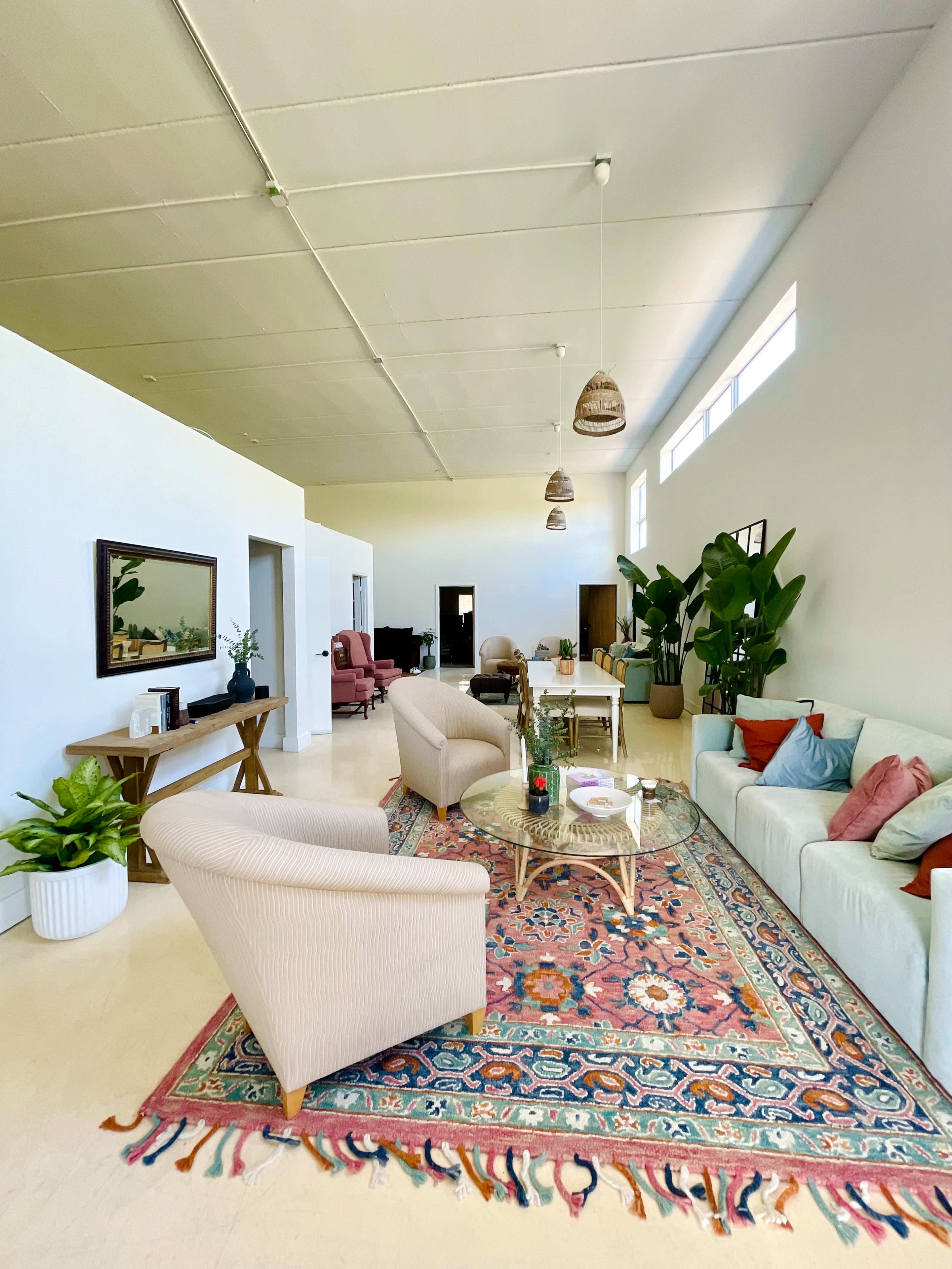 A spacious, well-lit living area with a mix of seating options, a coffee table, and decorative plants.