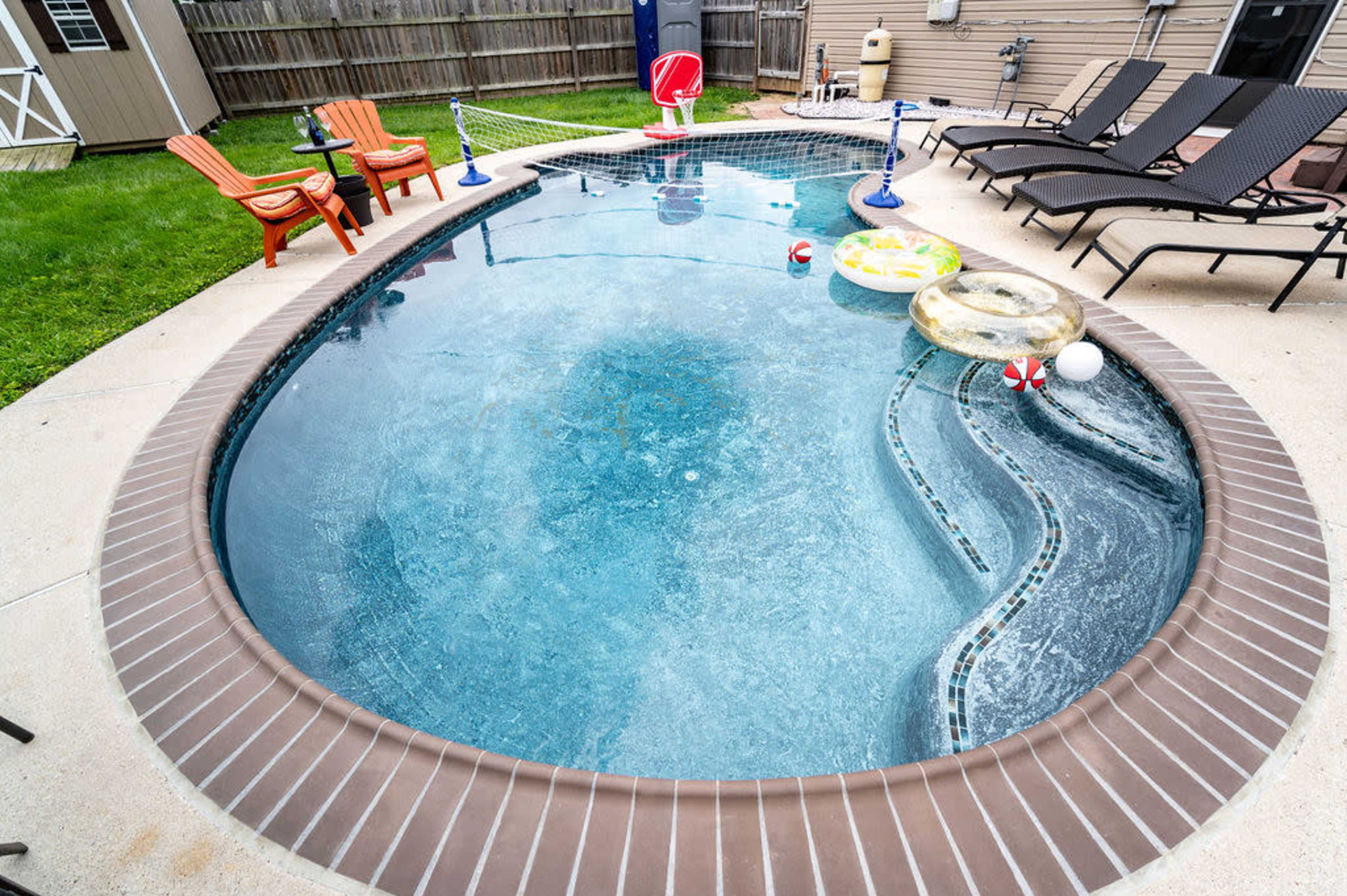 A kidney-shaped swimming pool surrounded by lounge chairs and floating toys.