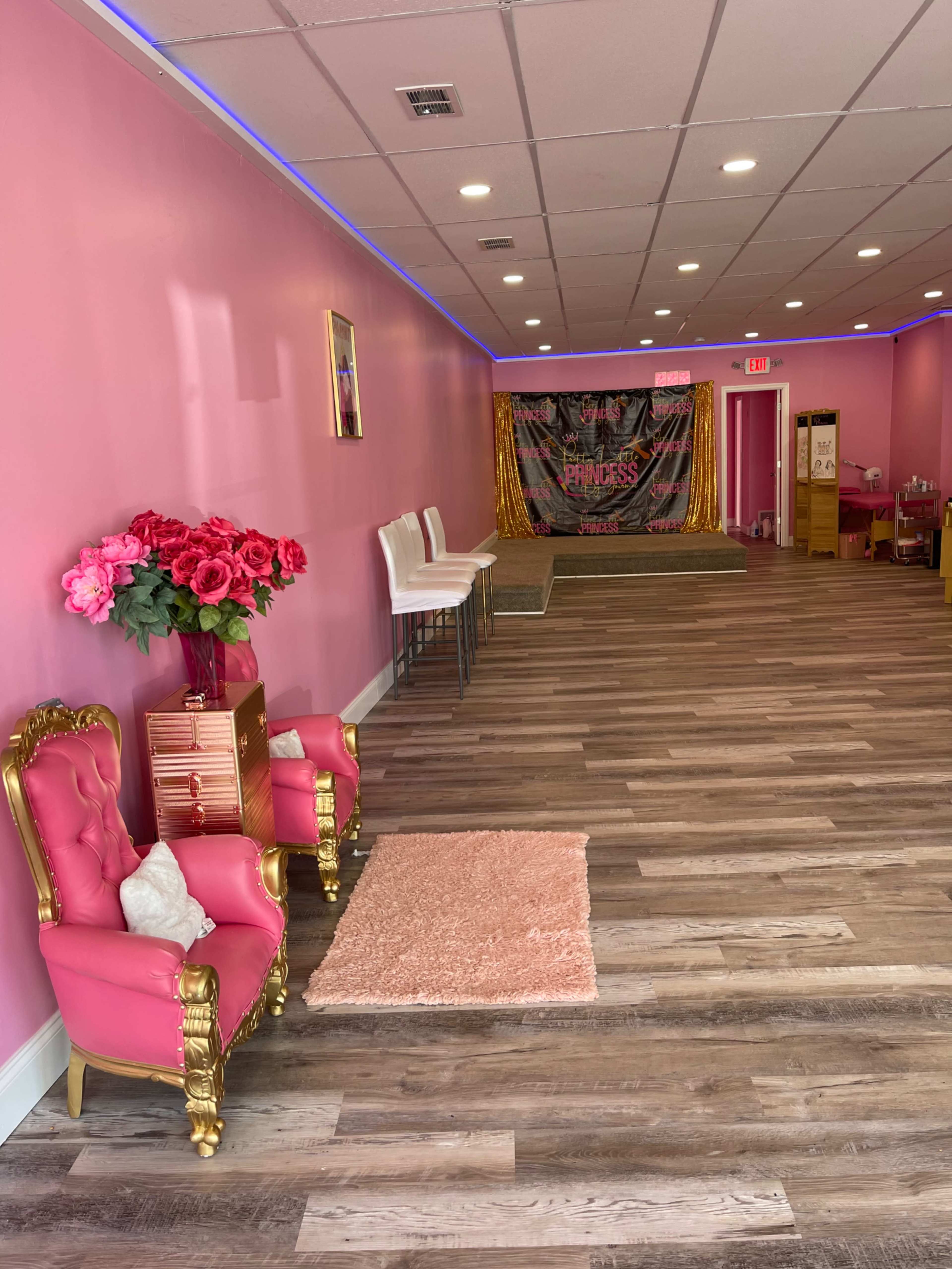 The interior of a pink-themed space features two ornate chairs, a decorative rug, and a backdrop with the word "Princess" on it.