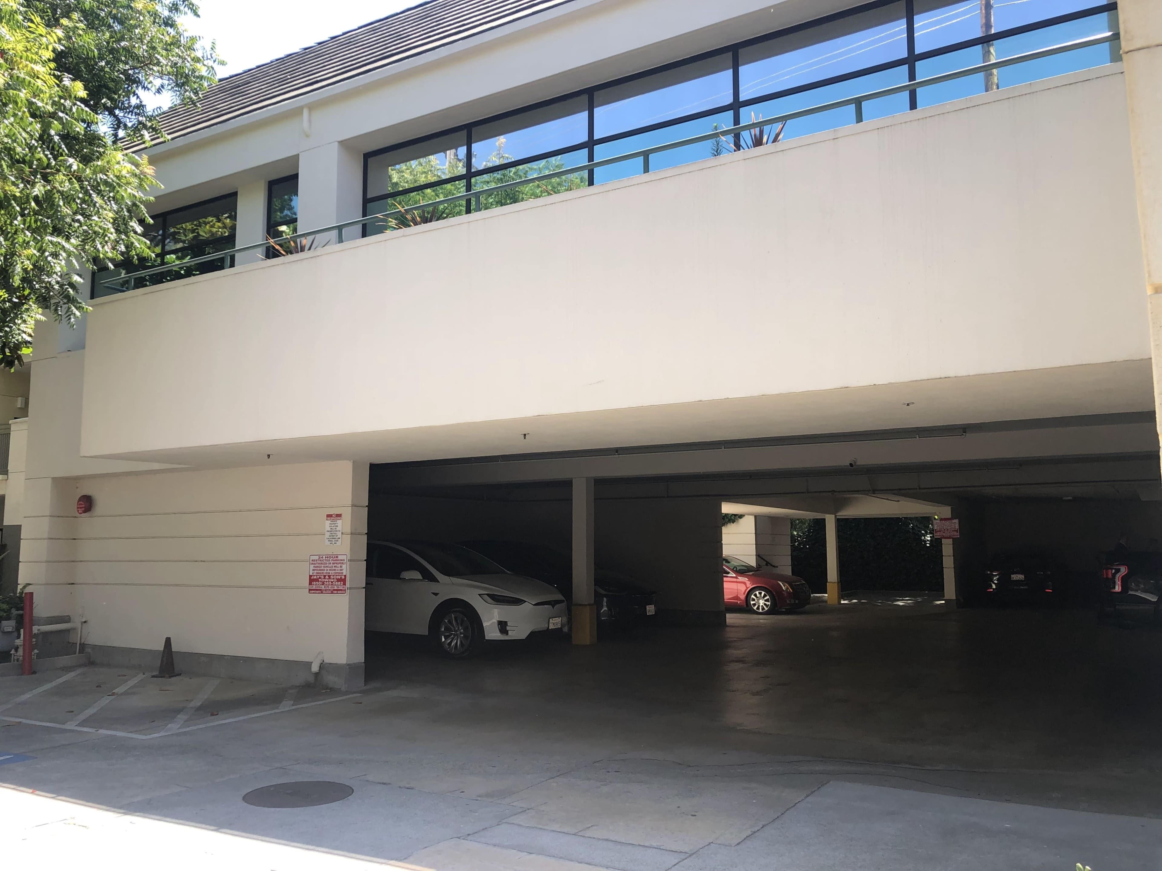 The image shows a partially shaded parking garage with two vehicles visible and a large window above.
