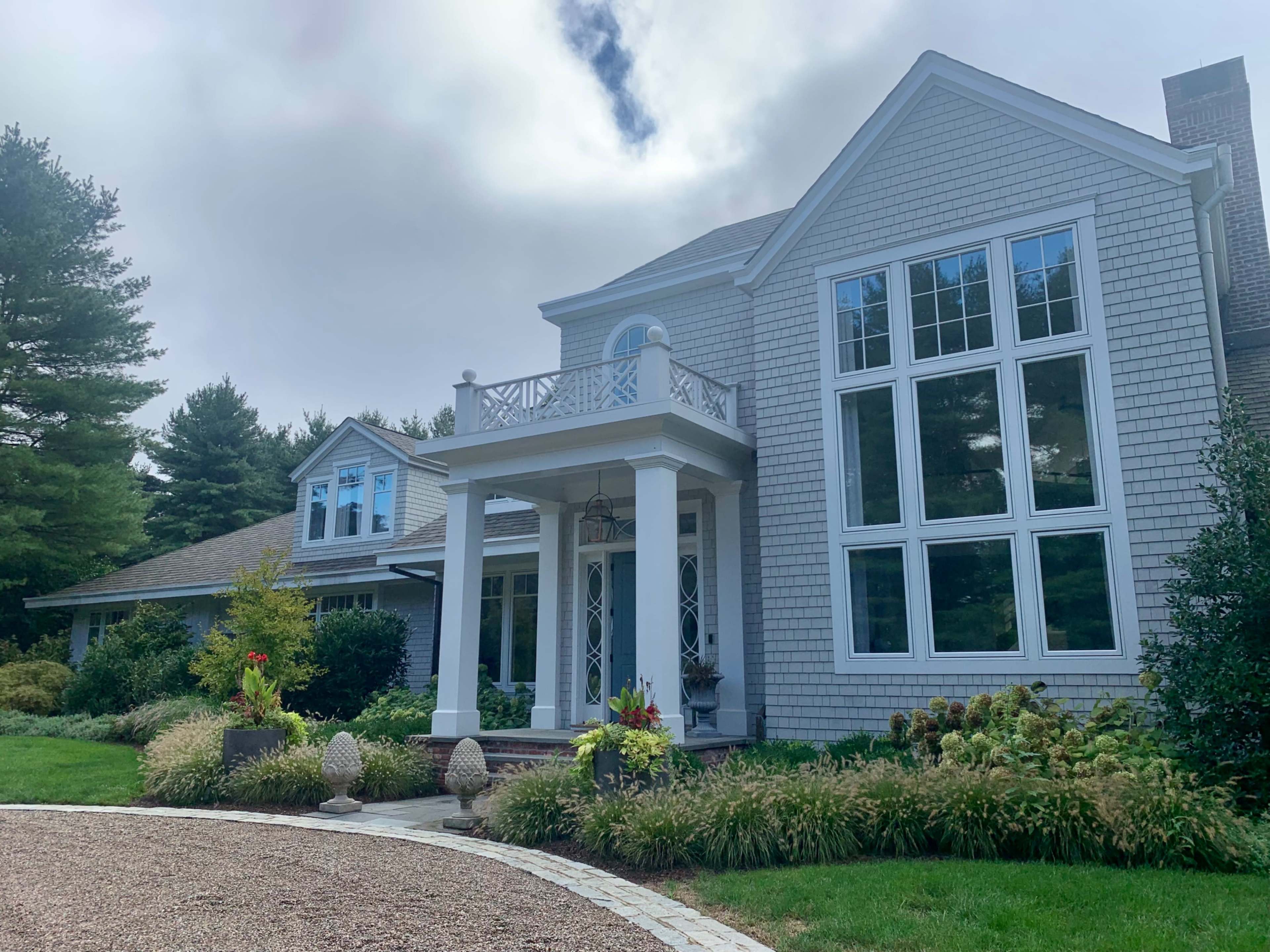 A large, modern house with multiple windows and a front porch is set in a landscaped yard.