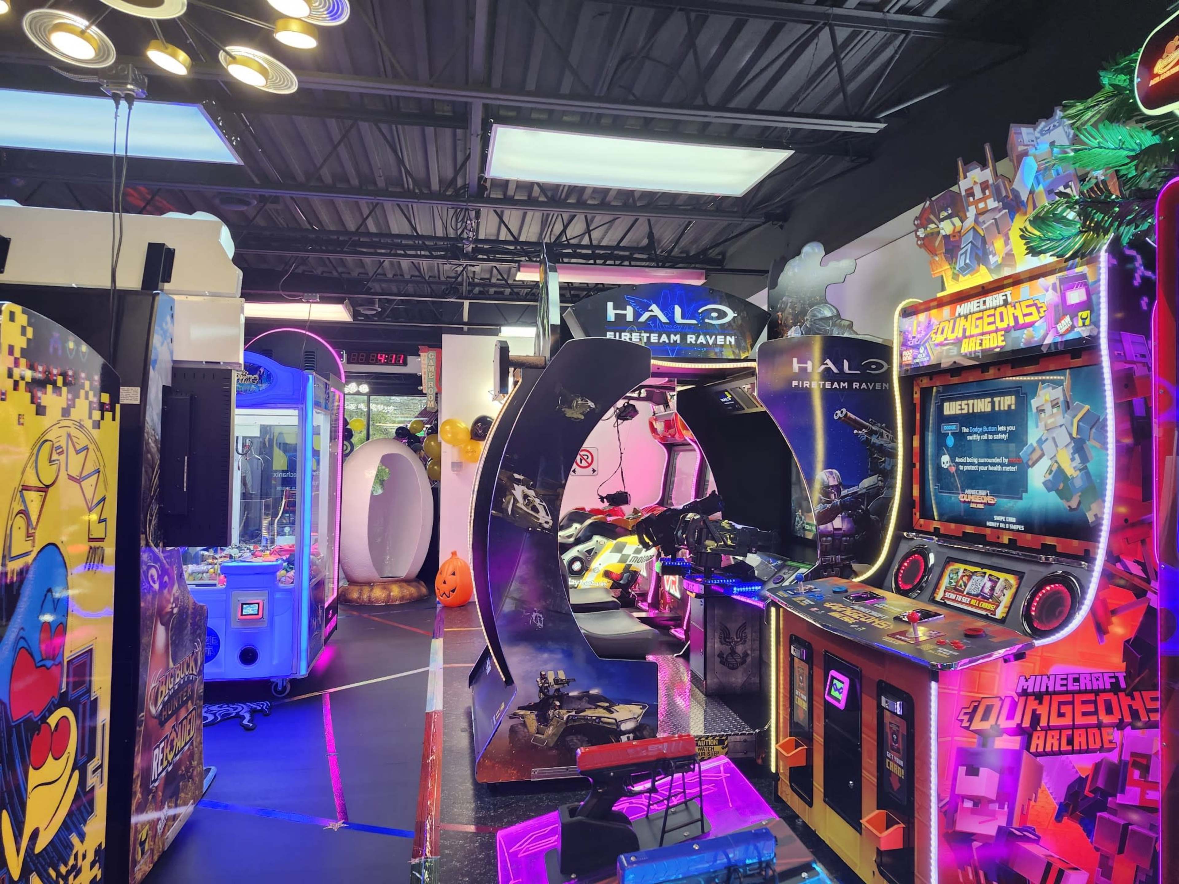 The image shows an arcade filled with various gaming machines, including a "Halo" shooting game and a "Minecraft Dungeon" arcade cabinet, all under bright lighting.