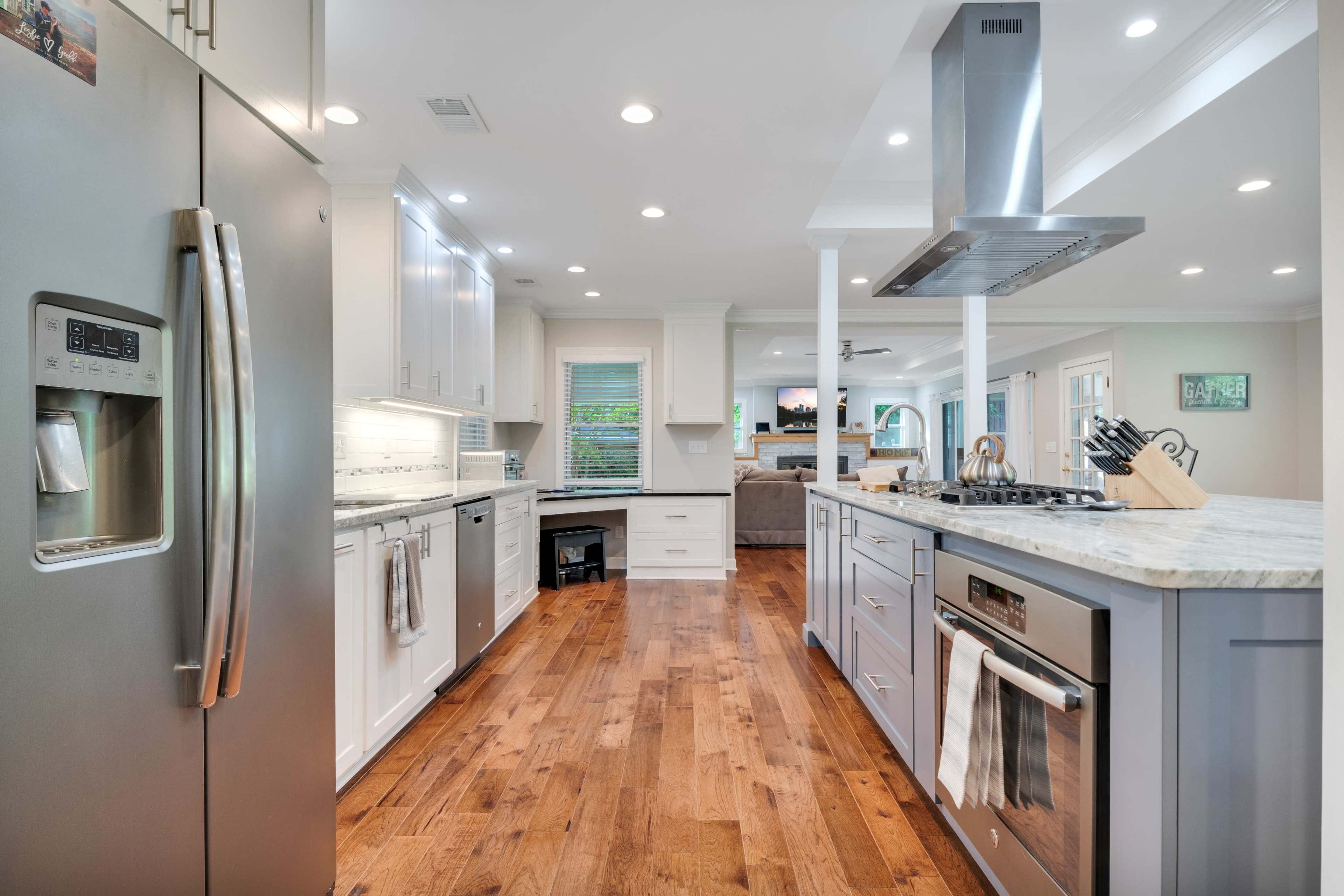 A modern kitchen features stainless steel appliances, a center island with a stove, and wooden flooring.