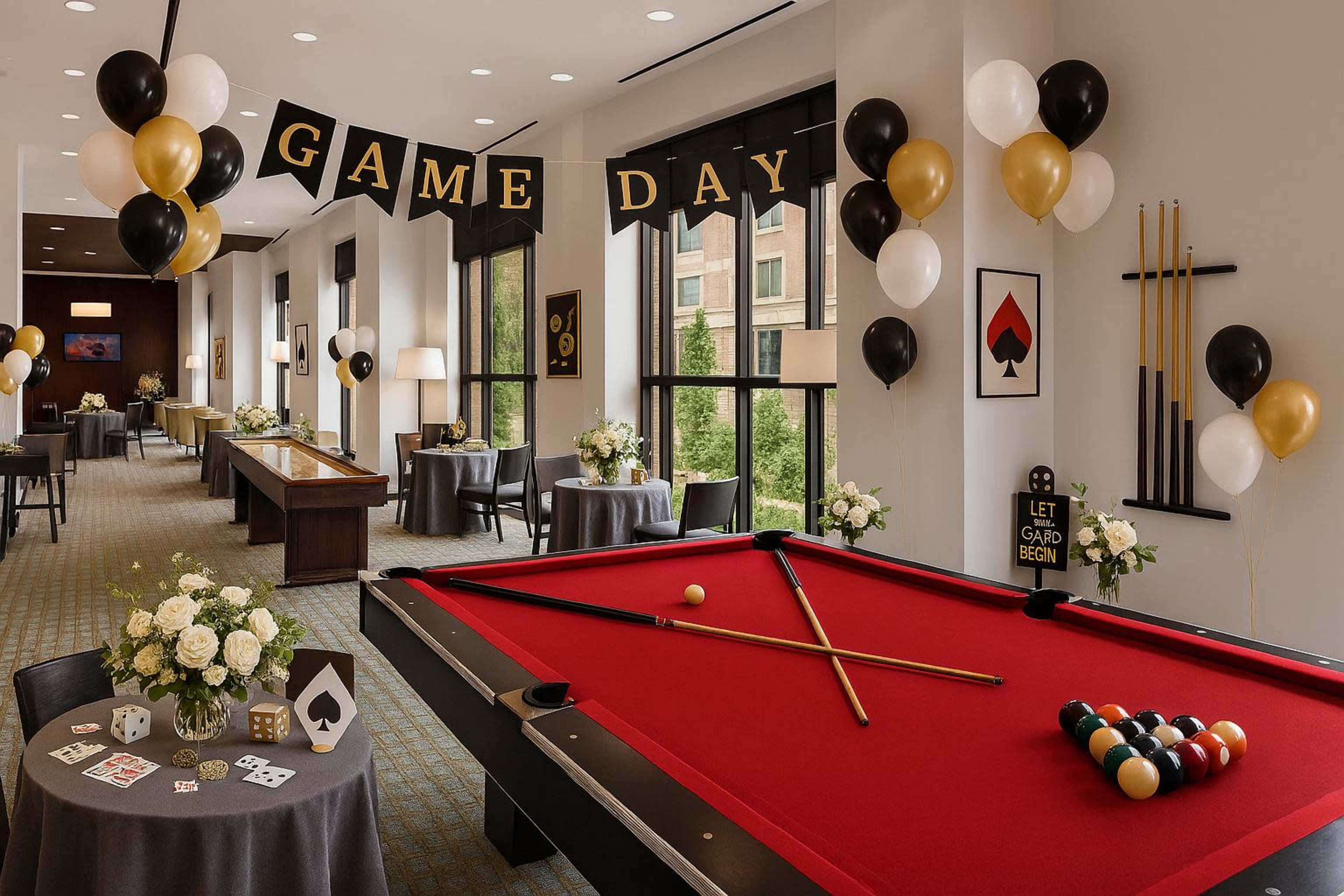 The image depicts a festive game day event setup featuring a red pool table, elegant flower arrangements, and black and gold decorations including balloons and banners.