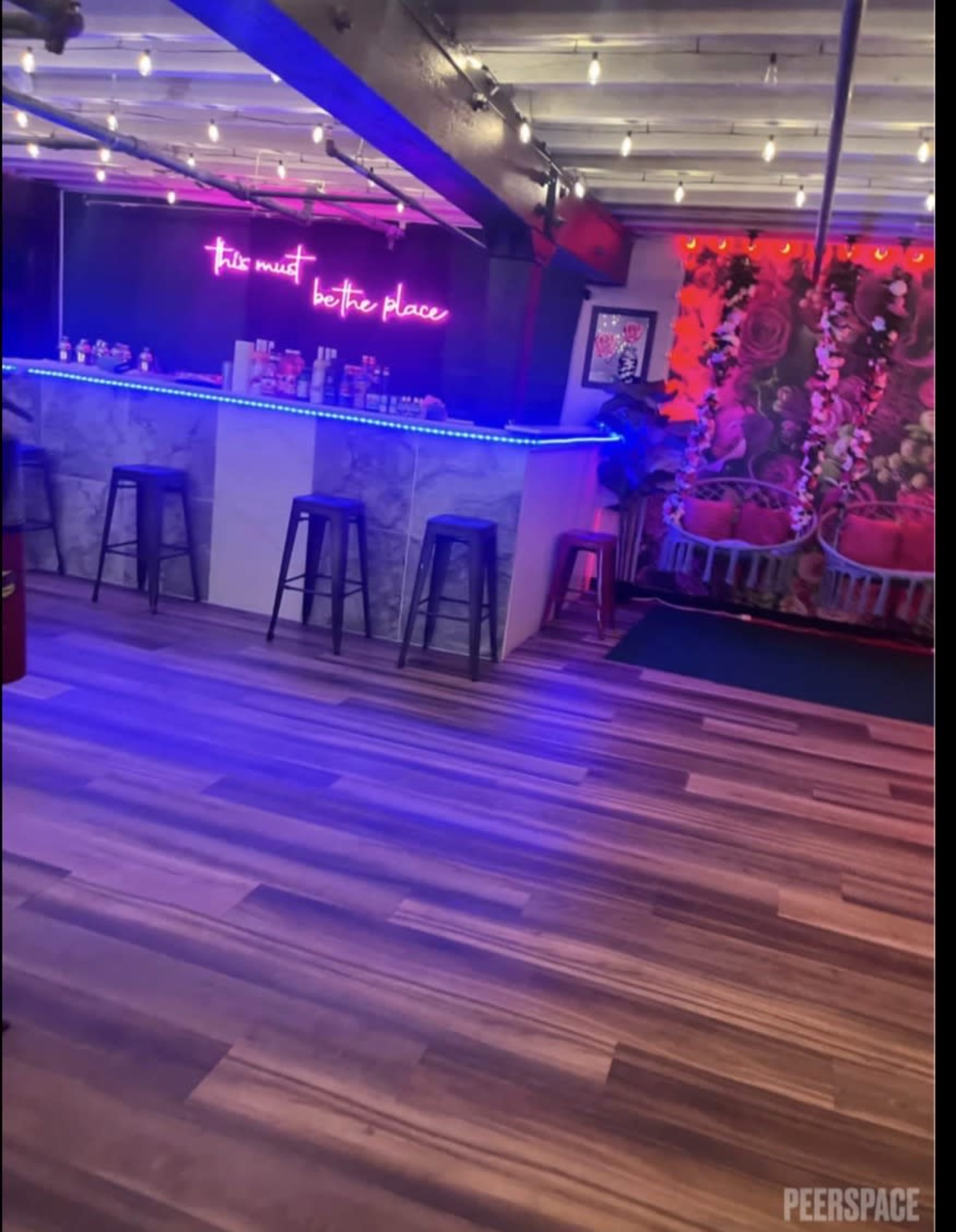 The image shows a modern bar area with a LED-lit counter, stools, and decorative lighting in a stylish interior.