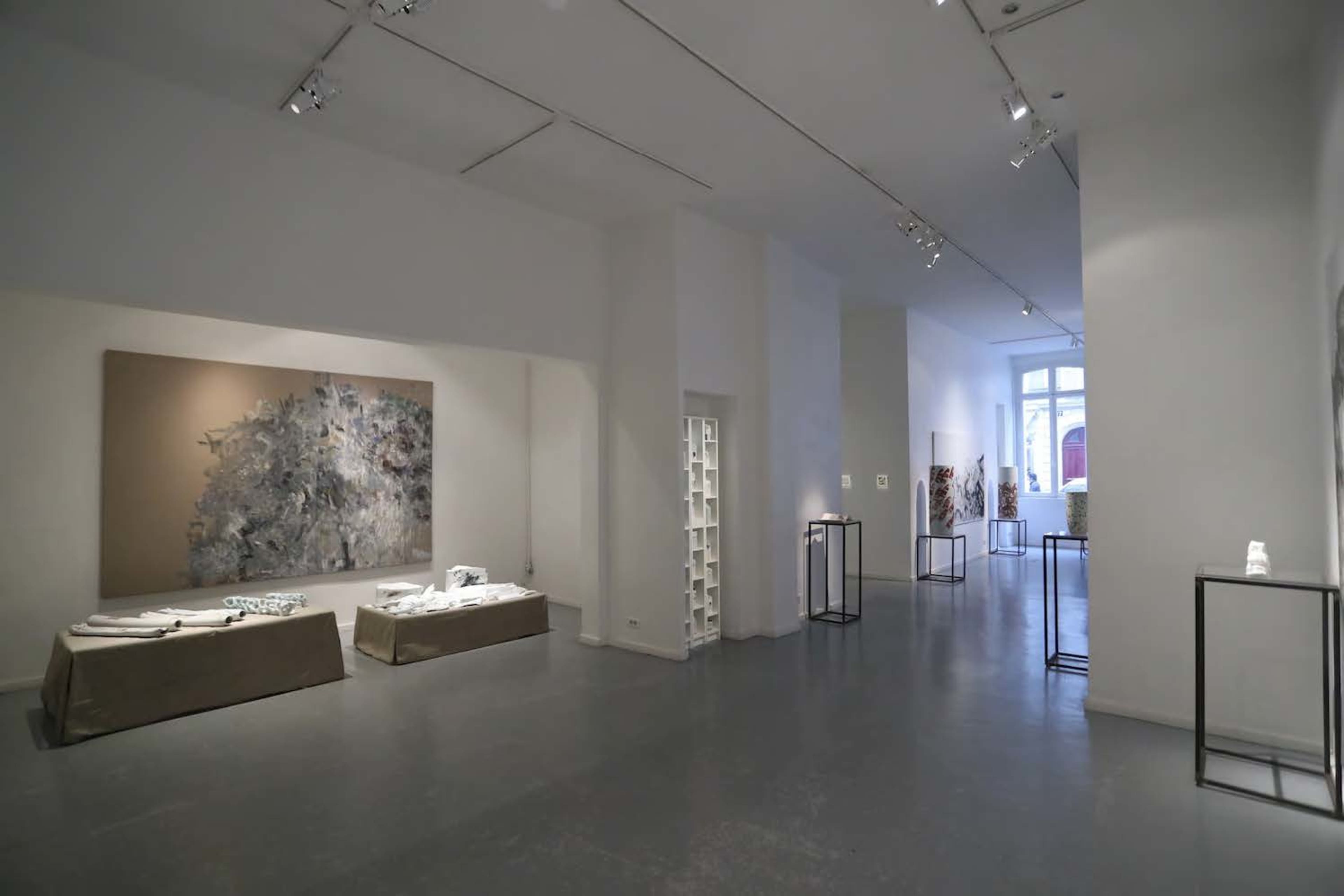 A clean, modern art gallery featuring various artworks displayed on the walls and pedestals.