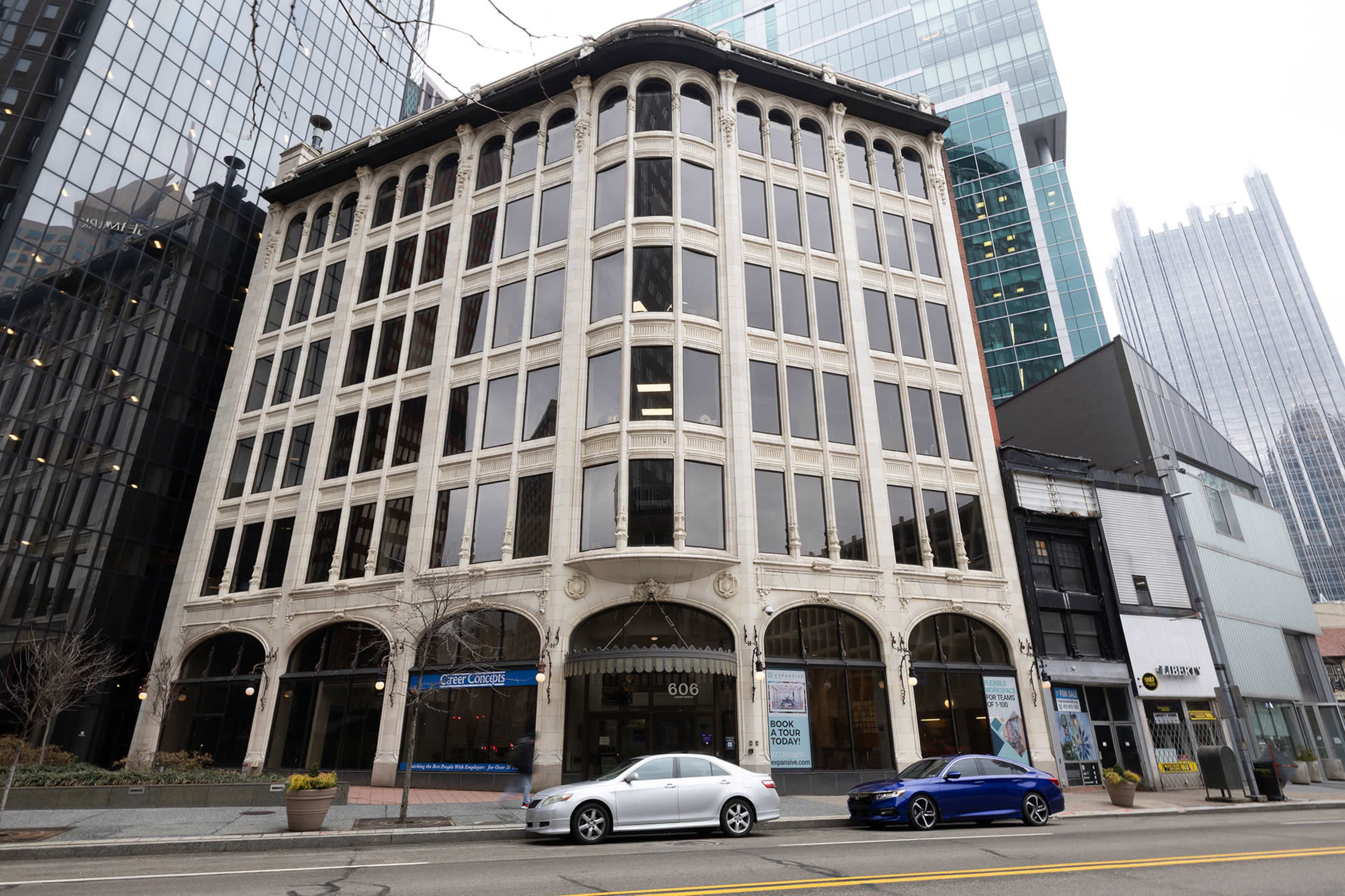 The image shows a multi-story building with a decorative facade at 606 in a city street, flanked by modern skyscrapers.