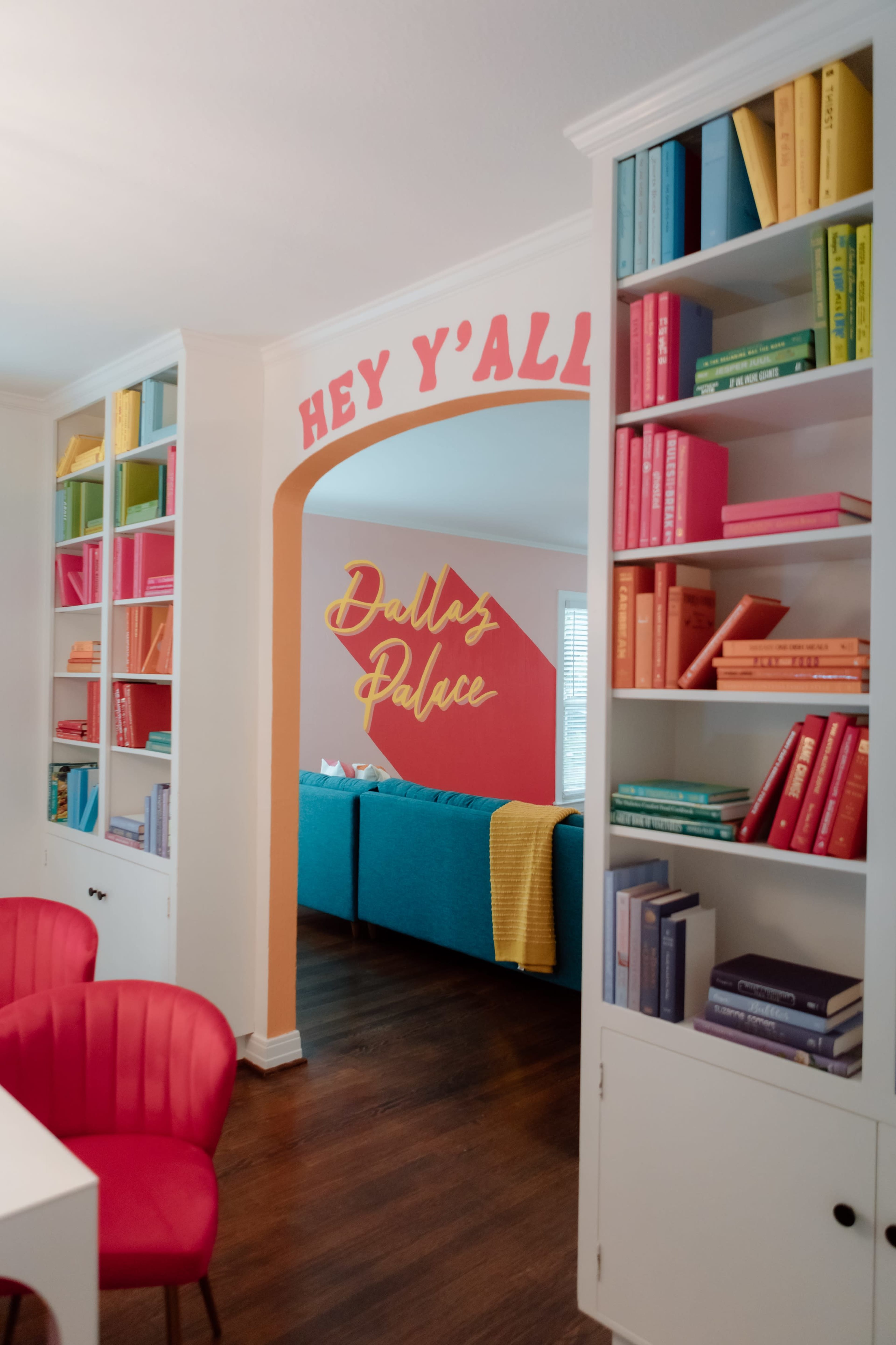 A brightly colored room features an archway labeled "Dollaz Palace," with shelves filled with vibrant books and modern furniture.