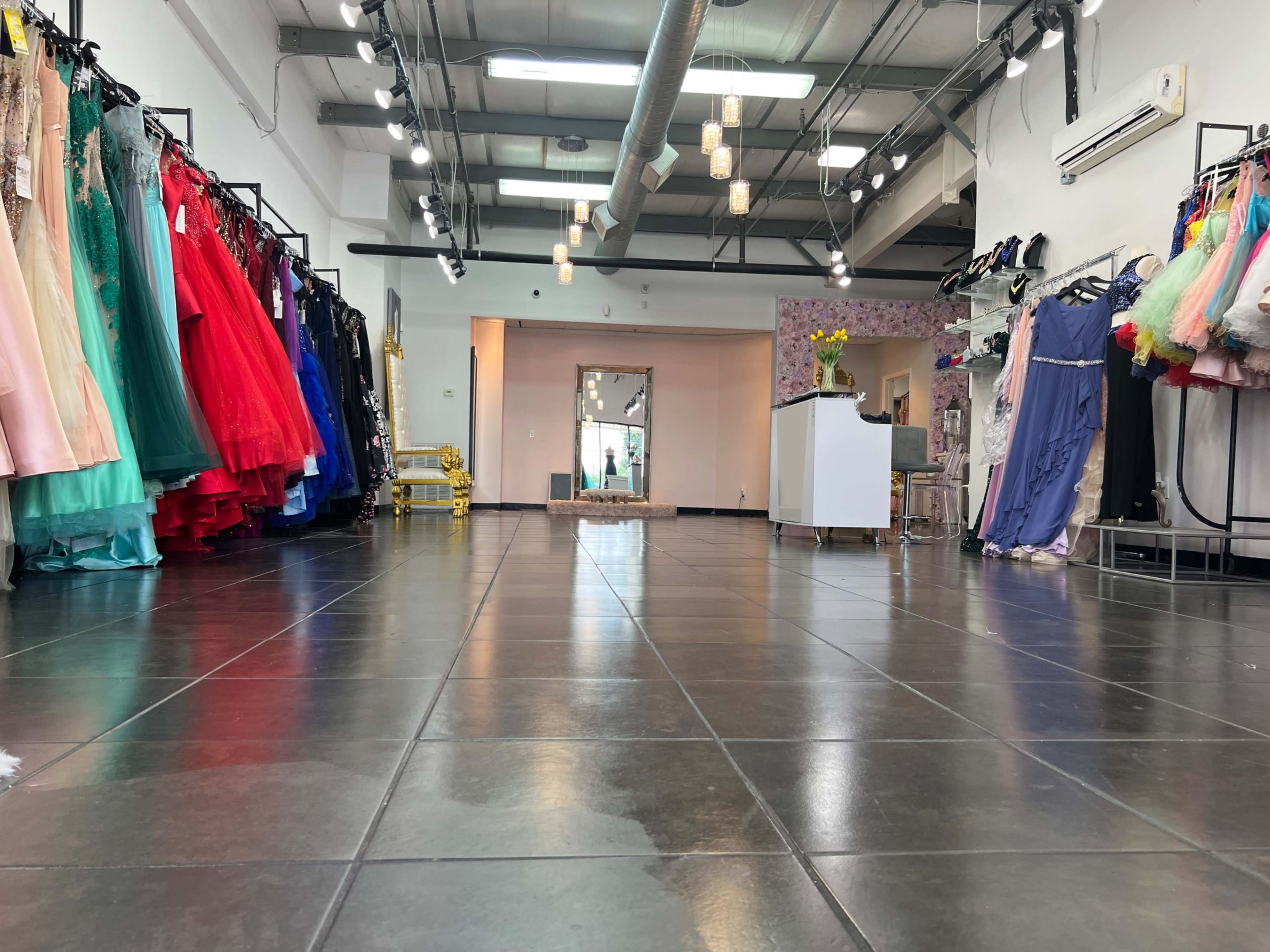 The interior of a boutique with racks of colorful dresses lining the walls and a reception desk in the center.