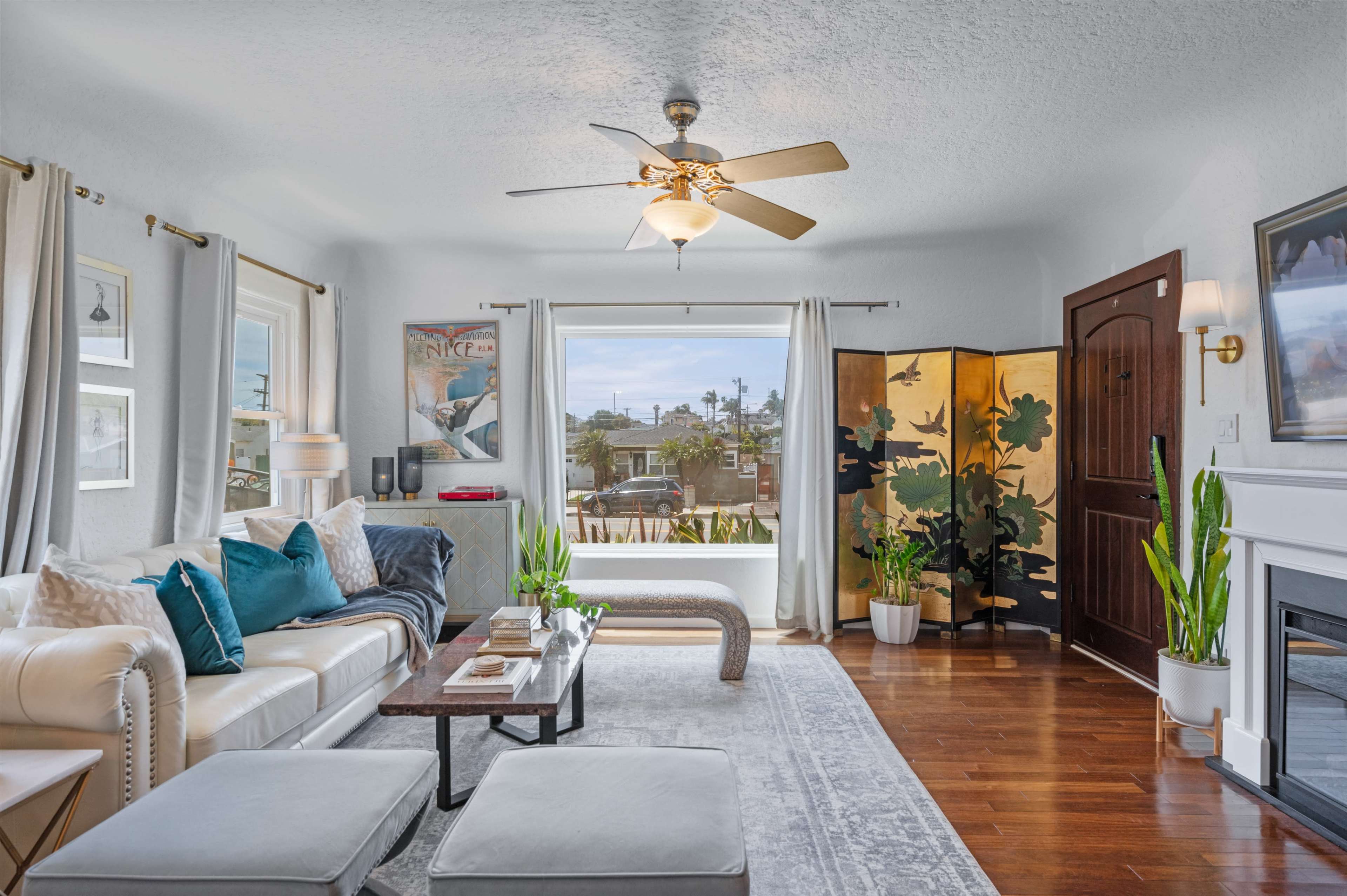 A well-furnished living room with a cream-colored sofa, a coffee table, and large windows overlooking an outdoor view.