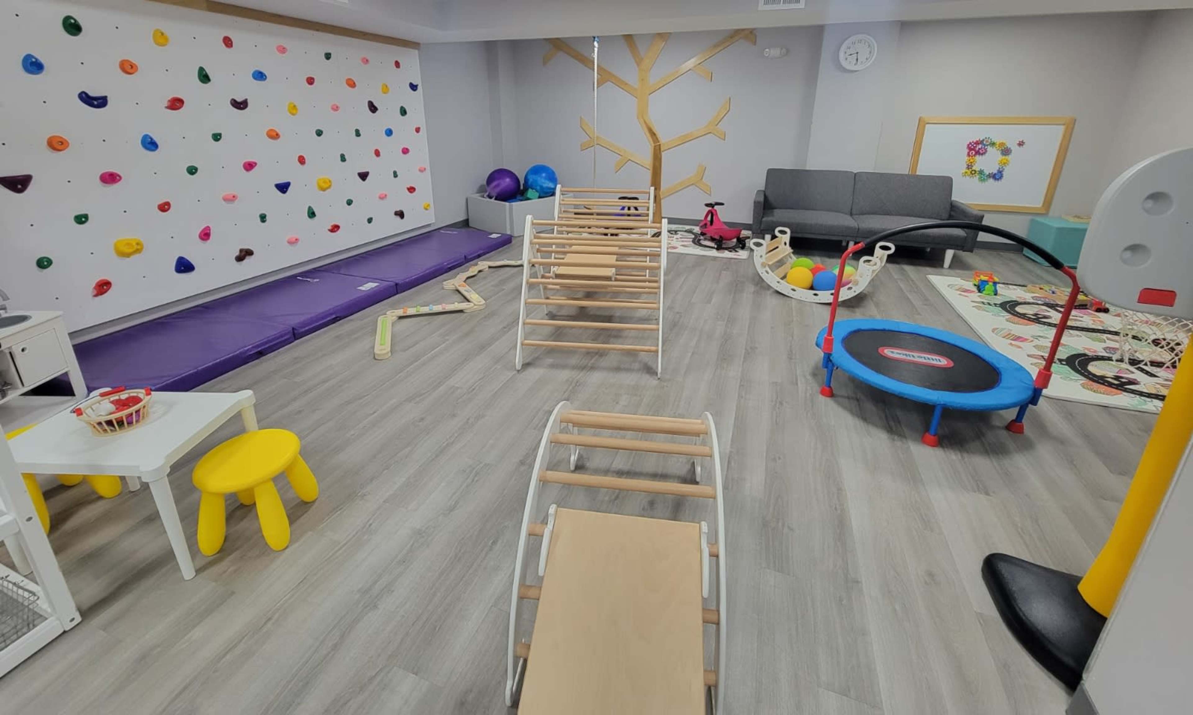 A colorful children's playroom equipped with climbing walls, soft play equipment, and various toys.