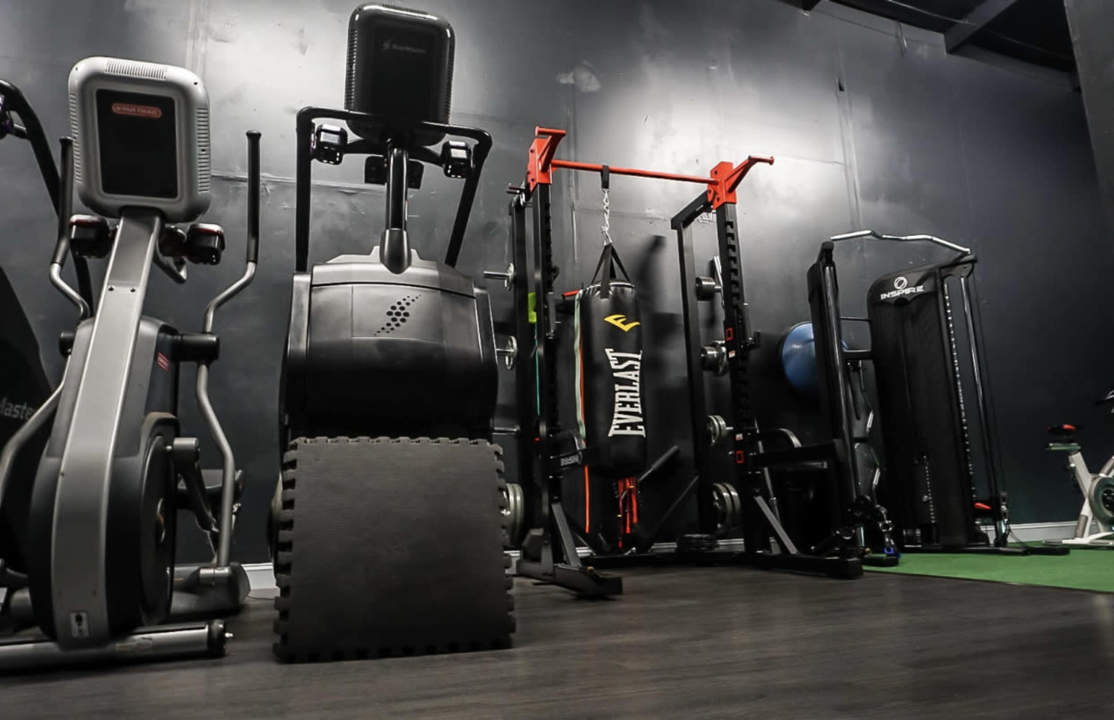 A gym interior equipped with various exercise machines, weights, and a punching bag.