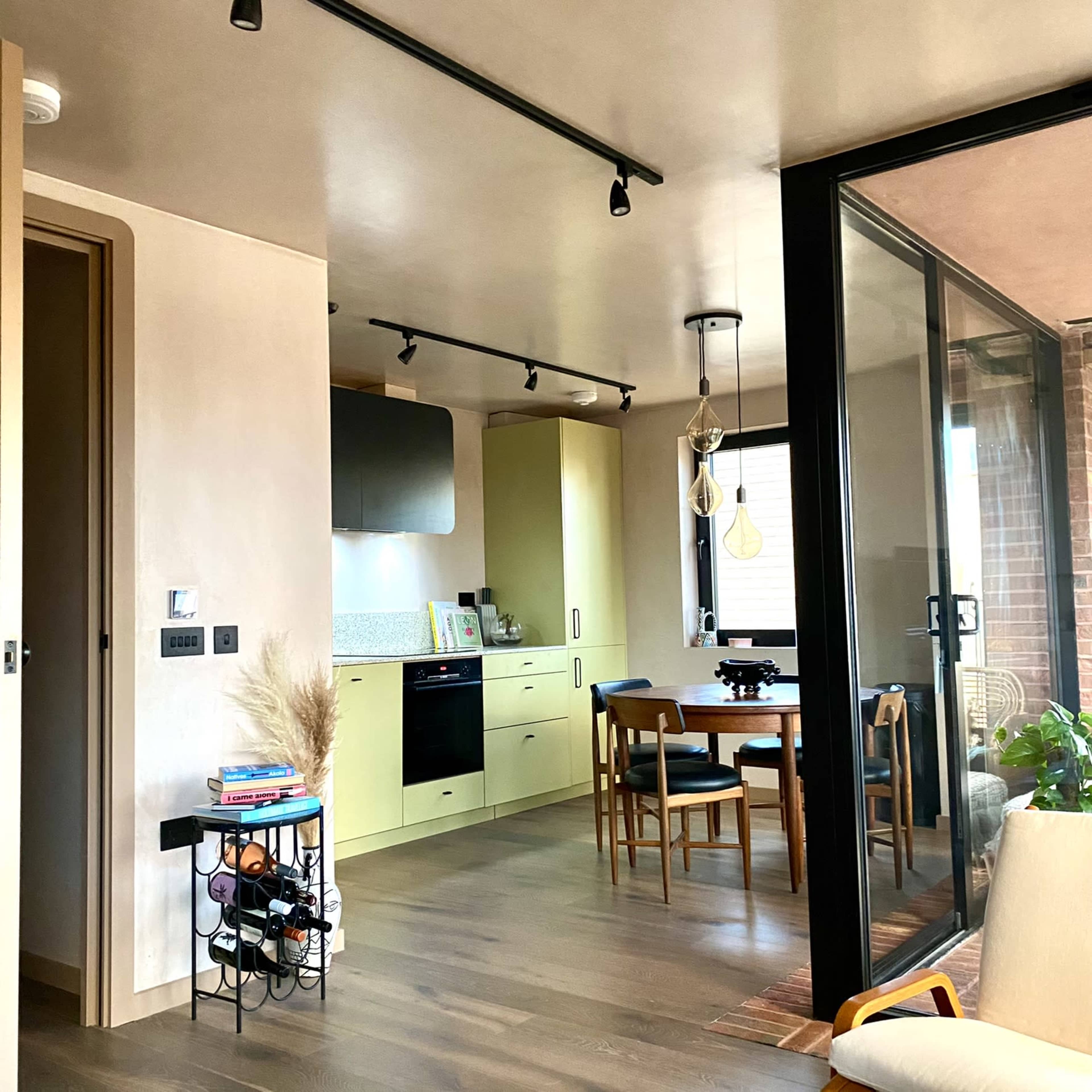 A modern kitchen with yellow cabinets and a dining area featuring a round table and chairs is visible in the open space.